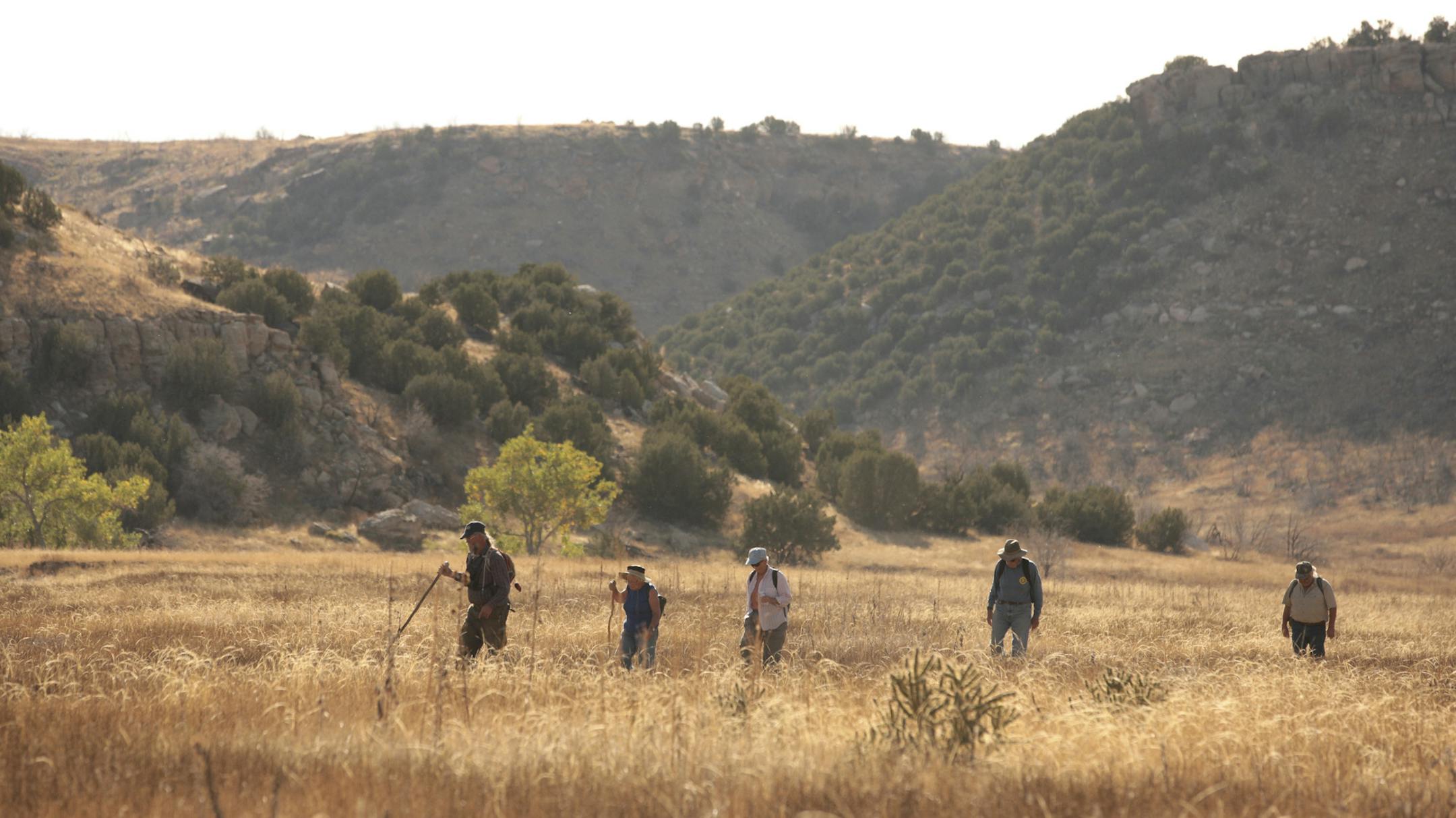 Kevin Lindahl, a part-time Forest Service employee, and volunteer excavators walk toward a starting point for a morning of surveying in Picketwire Canyon in southeast Colorado, Oct. 15, 2015. The canyon has too many dinosaur bones and too few people to excavate them, so the Forest Service has benefited from the help of a small group of amateur volunteer sleuths, many in their 70s and 80s. (Matthew Staver/The New York Times)