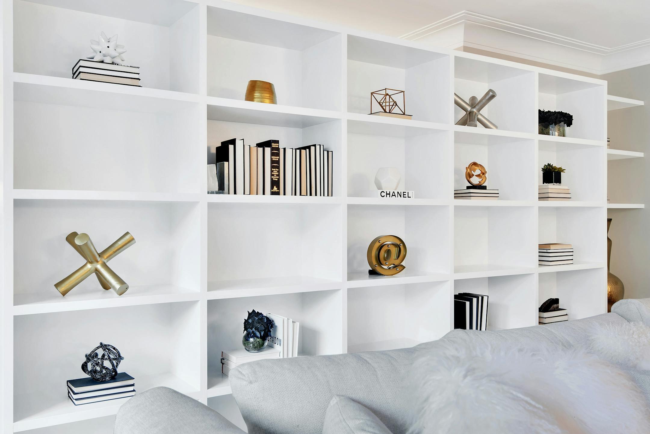 A mix of small- and medium-sized gold accent pieces helps create drama in this bookcase display. (Design Recipes) ORG XMIT: 1222674
