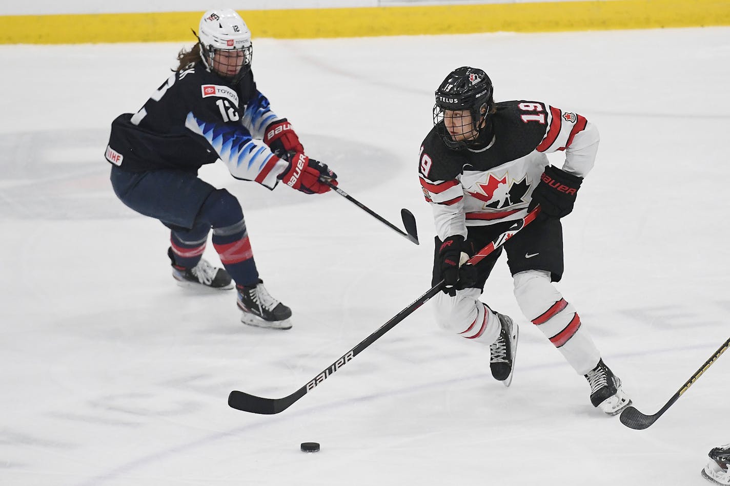 Canada's Brianne Jenner (19) works the puck against United States' Kelly Pannek (12) during the first period of a women's exhibition hockey game ahead of the Beijing Olympics, Friday, Dec. 17, 2021, in Maryland Heights, Mo. (AP Photo/