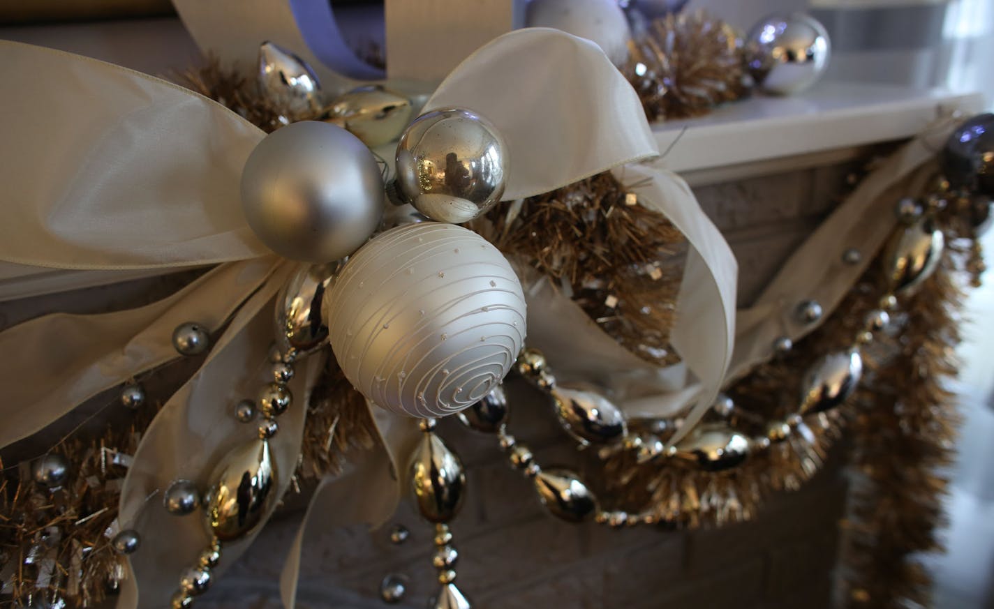 Interior Designer Lisa Peck of Lilu Interiors, decorated the mantel with lights, ribbon, garland and ornaments keeping the sliver, gold and ivory color scheme in her home in Minneapolis, Thursday, November 20, 2013. ] (KYNDELL HARKNESS/STAR TRIBUNE) kyndell.harkness@startribune.com