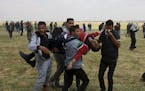 Palestinian protesters evacuate a wounded youth during clashes with Israeli troops along the Gaza Strip border with Israel, east of Khan Younis, Gaza 