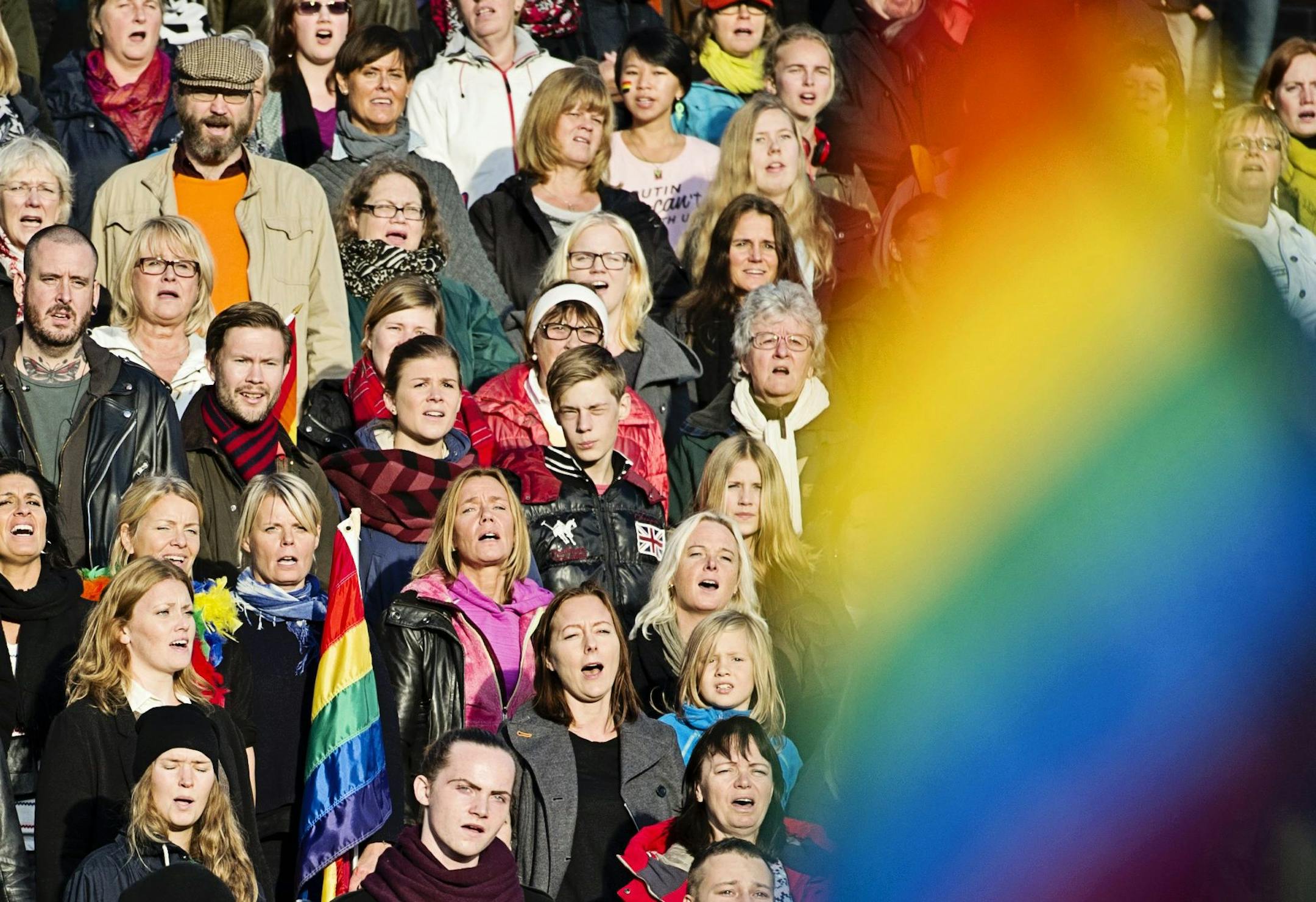 A crowd of people sing the Russian National Anthem, at the Stockholm Olympic Stadium on Sunday Oct. 6, 2013, while raising rainbow flags in solidarity with the Russian lesbian, gay, bisexual and transgender (LGBT) community. A project called 'Live and Let Love' is expected to use footage from the event to be cut together with other singers and musicians from around the world to make a video film that will be shown on YouTube ahead of the Olympic games in Sochi. (AP Photo/TT News Agency/Erik Mart