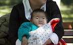 A child is wrapped up against the cold at a park in Beijing, China, Friday, Oct. 30, 2015. Shares of companies making diapers, baby strollers and infa