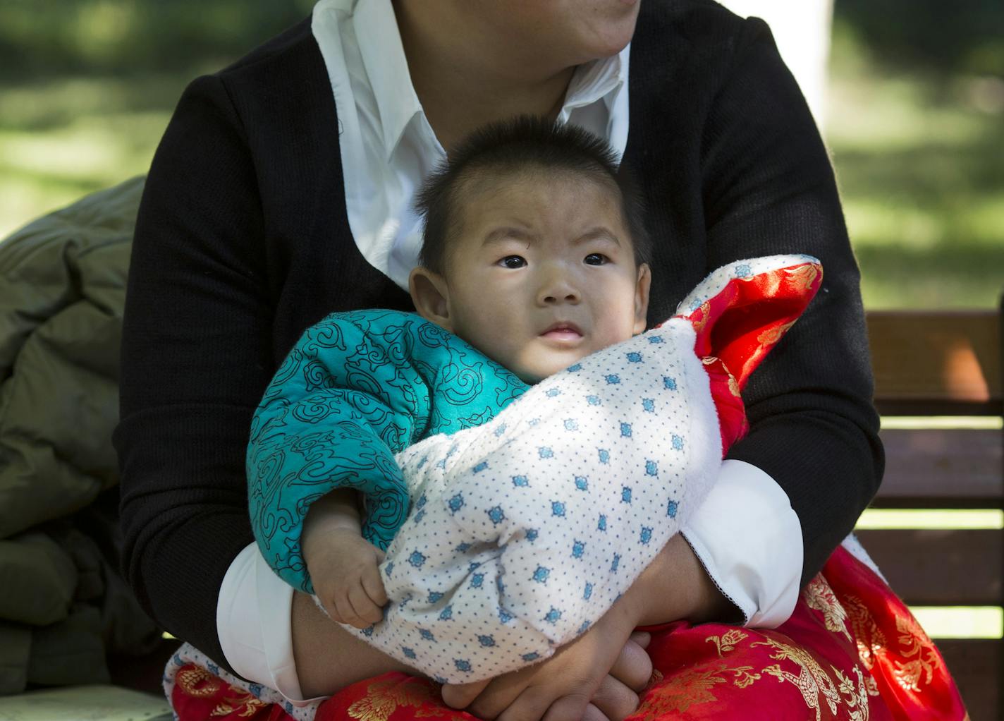 A child is wrapped up against the cold at a park in Beijing, China, Friday, Oct. 30, 2015. Shares of companies making diapers, baby strollers and infant formula were getting a boost Friday from China's decision to scrap its decades-old one-child policy. (AP Photo/Ng Han Guan) ORG XMIT: XHG107