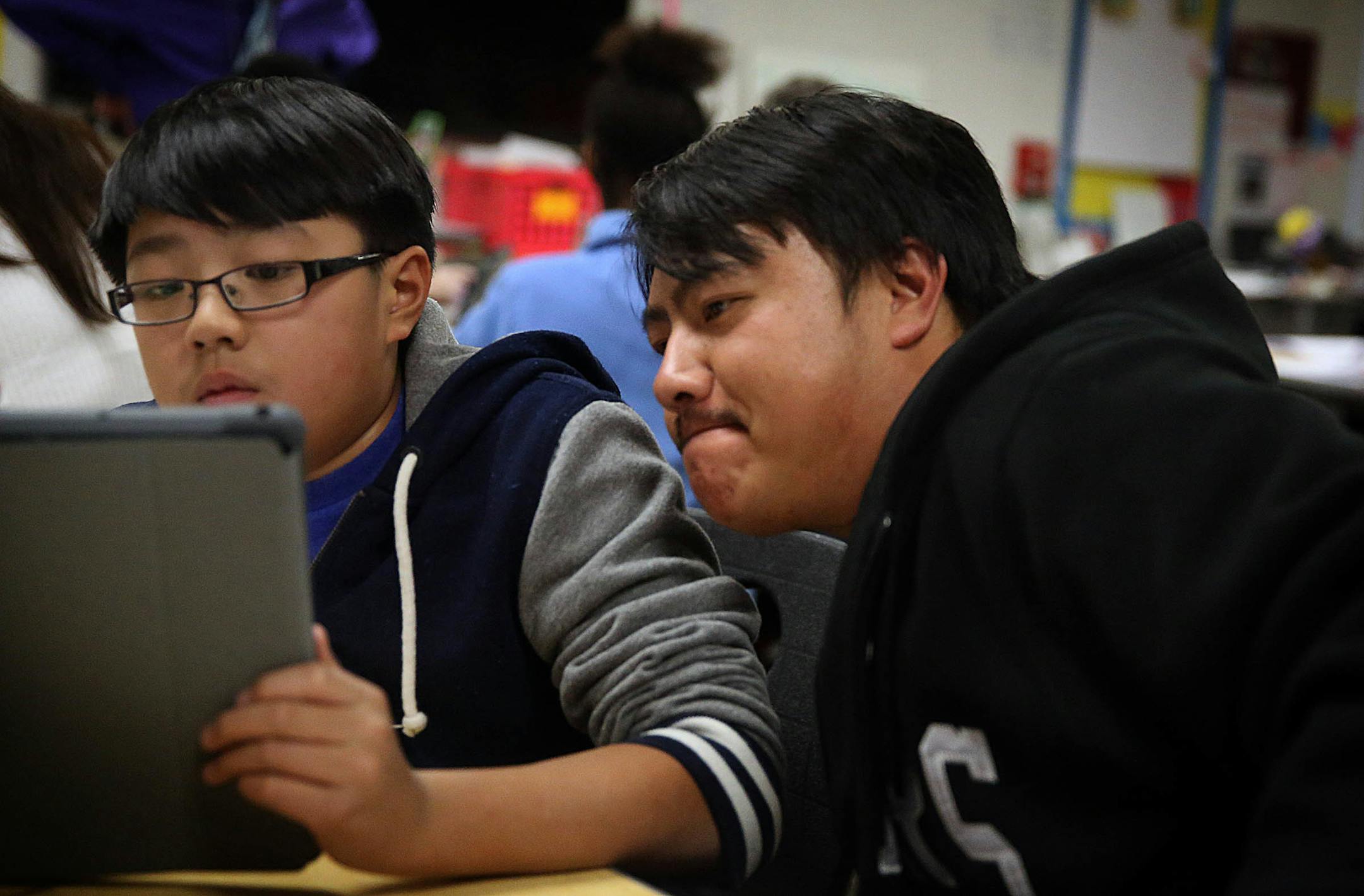 Parkway Middle School sixth grader Hunter Moua, 11, set up his iPad with the help of his father, Neng Moua. ]JIM GEHRZ • jgehrz@startribune.com / St. Paul, MN / Oct. 7, 2014 / 4:00 PM / BACKGROUND INFORMATION: In a low key rollout, the St. Paul School District's grand experiment with iPads begins quietly Tuesday when students at Parkway Middle School become the first in the district to pick up the high tech equipment. Students will receive their iPads at 4 p.m. and attend an orientation session