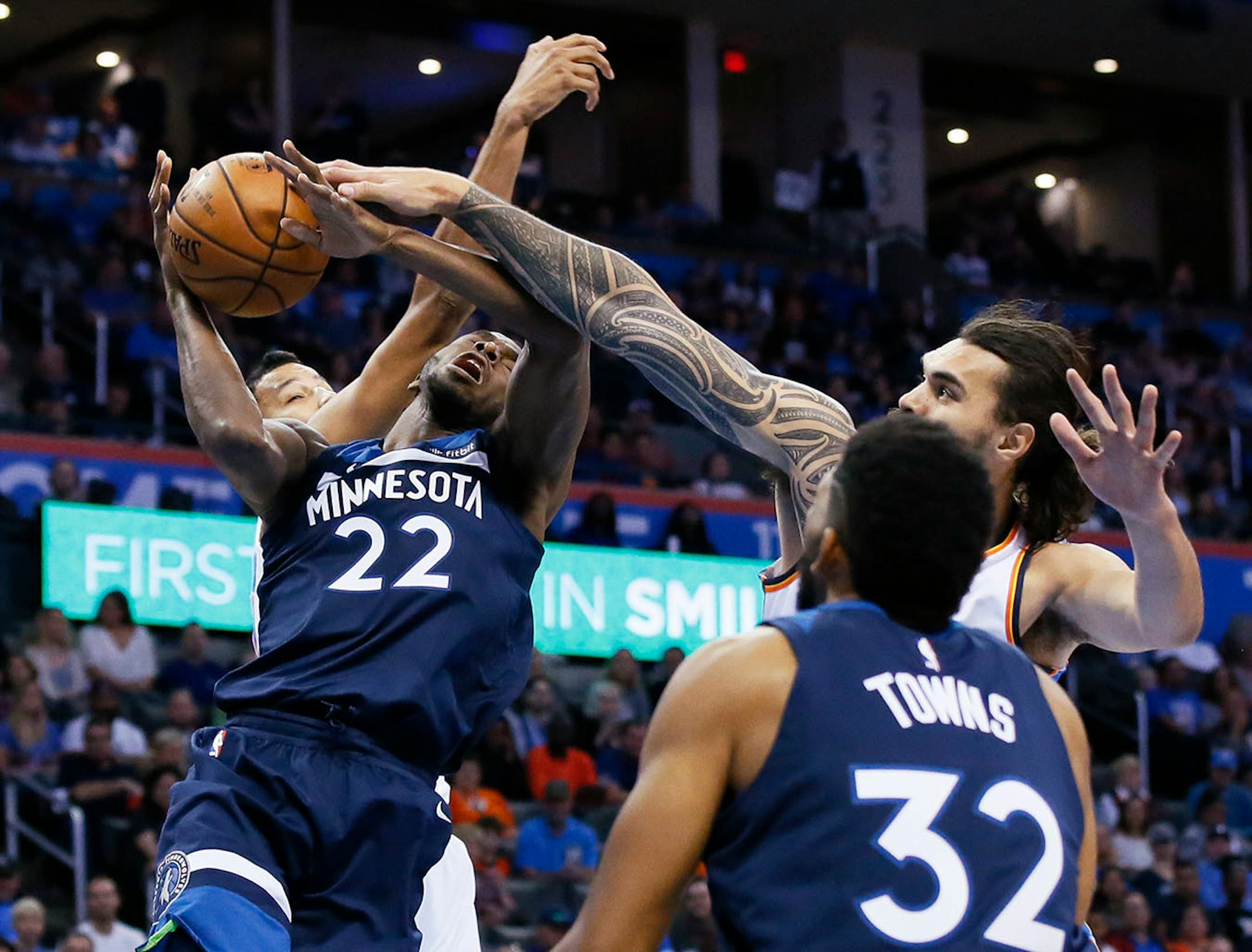Minnesota Timberwolves guard Andrew Wiggins (22) is fouled by Oklahoma City Thunder center Steven Adams, right, as he shoots between Adams and Andre Roberson, left, in the first quarter of an NBA basketball game in Oklahoma City, Sunday, Oct. 22, 2017.