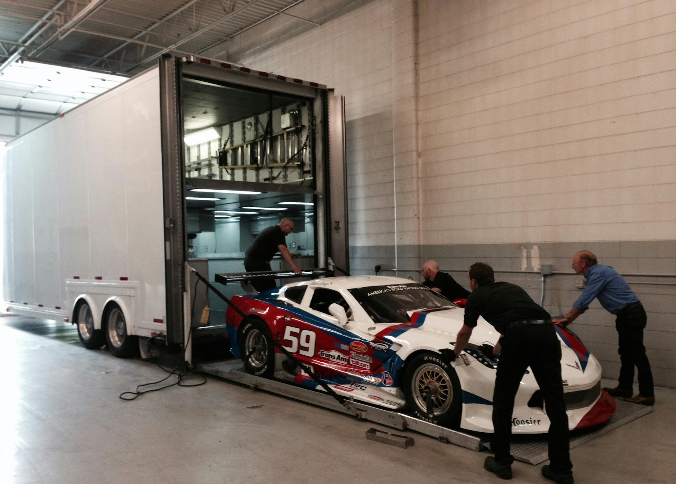 Jim Derhaag (far right) and other members of Derhaag Motorsports team on Wednesday loaded up one of the two Trans Ams they are bringing to Brainerd for races this weekend. Photo/Michael Rand