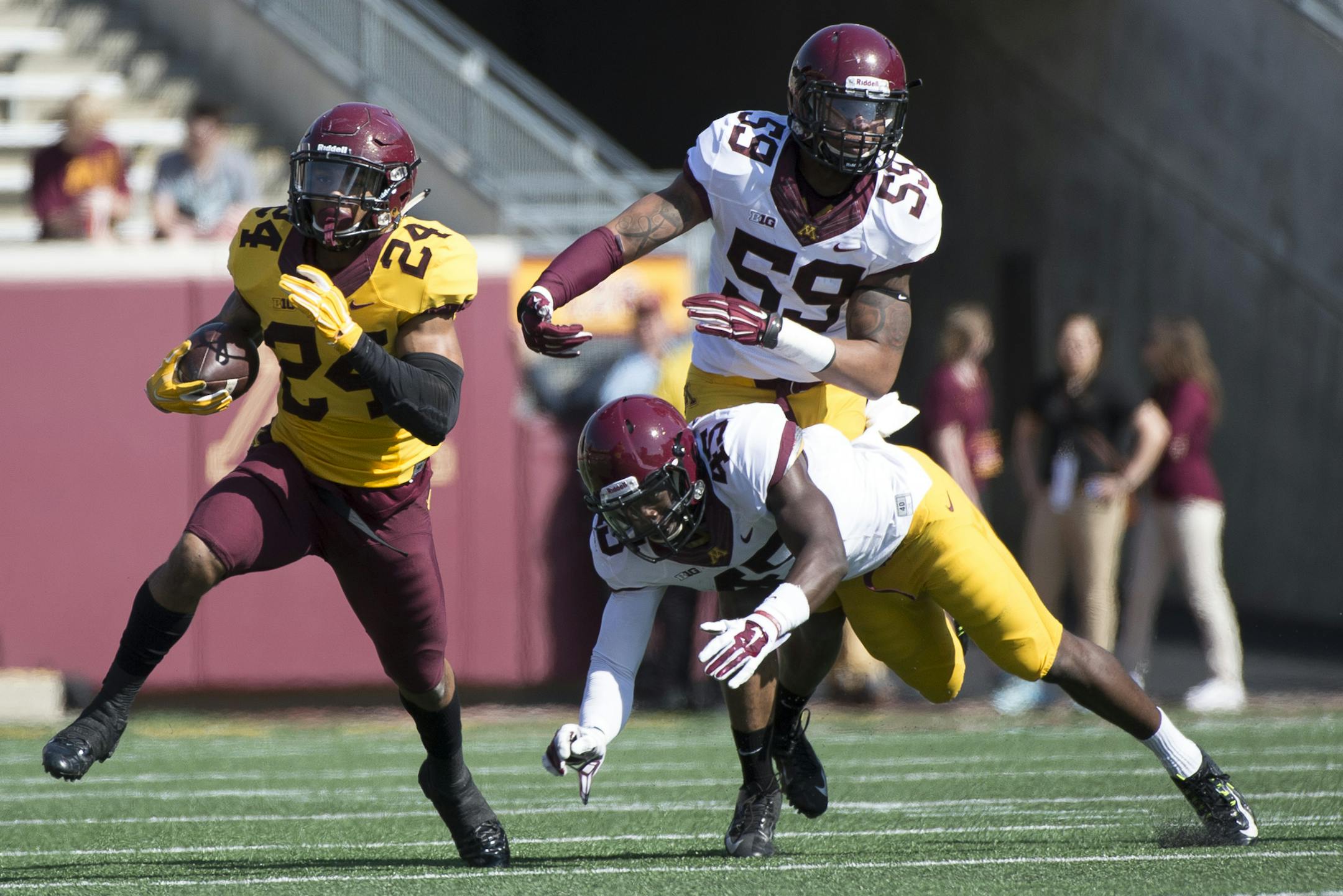 University of Minnesota running back Rodney Smith (24) breaks past defenders Adekunle Ayinde (45) and Ray Dixon (59) during the first half of Saturday's scrimmage. ] (Aaron Lavinsky | StarTribune) aaron.lavinsky@startribune.com The University of Minnesota football team participates in its annual spring game on Saturday, April 11, 2015 at TCF Bank Stadium in Minneapolis.