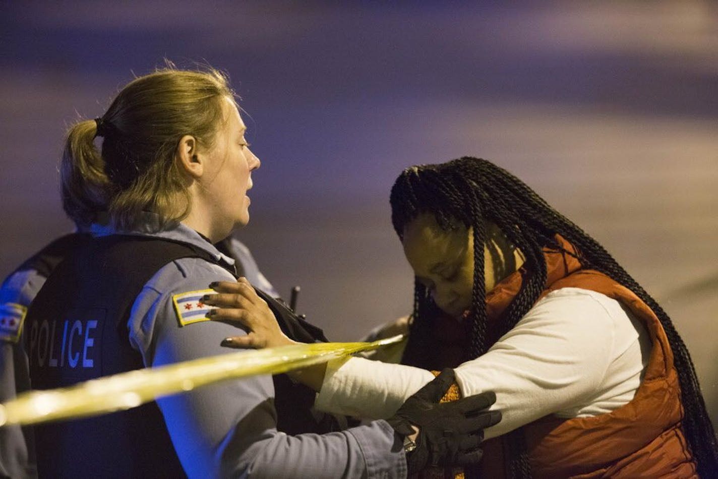 A member of the Chicago Police Department talks with Felicia Humphries at the scene where her son was shot and killed near the intersection of South Kilbourn Avenue and West Adams Street on Sunday, Oct. 25, 2015, in Chicago.