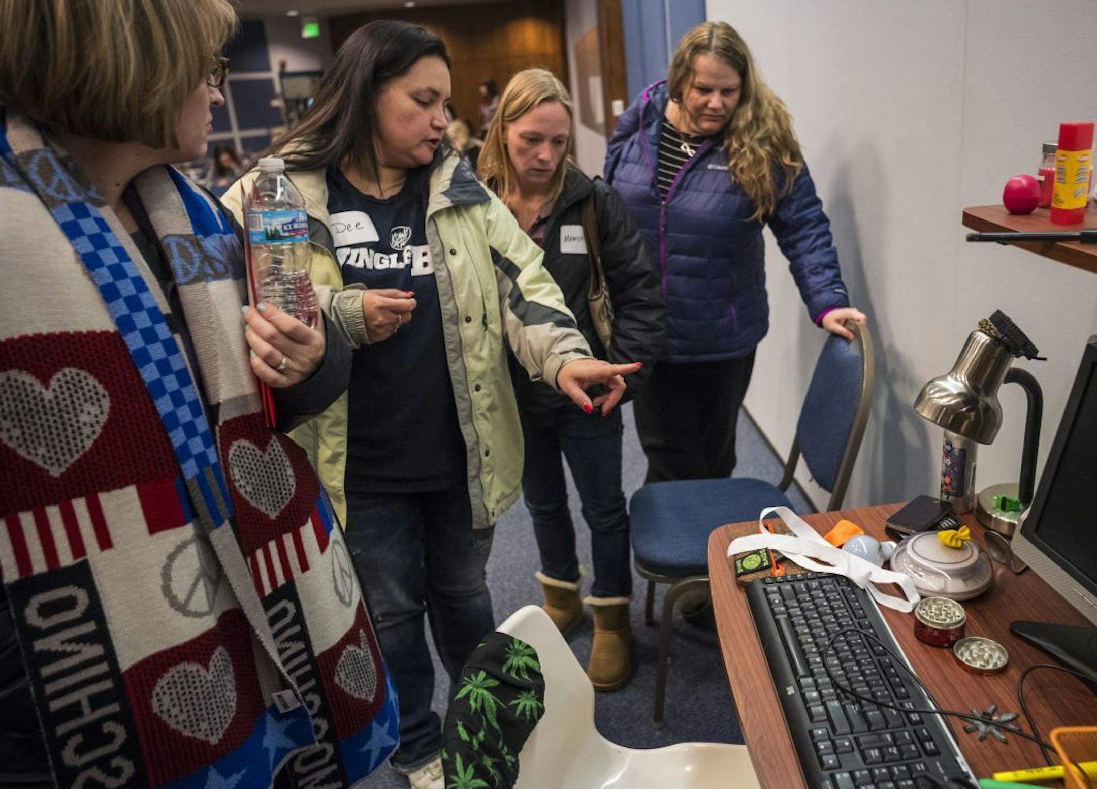 Dee Johnson,center, who had a child, now a young adult, go through the travails of drug addiction, pointed out to the other mothers signs of drug abuse at a mock student desk. These included a grinder for marijuana and a scale for drug dealing.