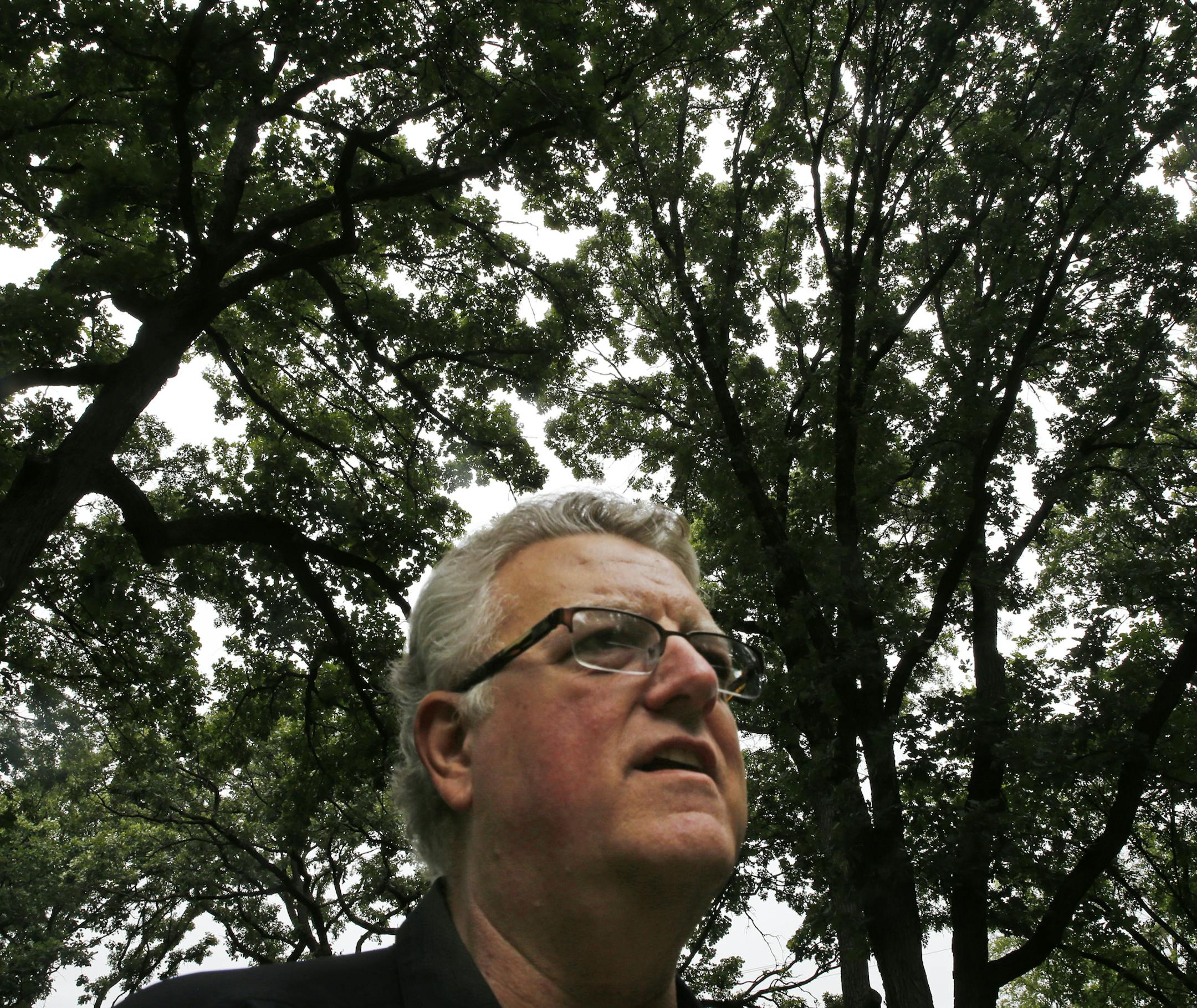 Joe Lais, CEO of Plantra, says a seedling protected with a tube is much more likely to grow into one like the huge old bur oaks behind him.
