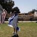 Draped in an Israeli flag, a pro-Israel supporter walks with an American flag near the pro-Palestinian encampment on the University of California, Los