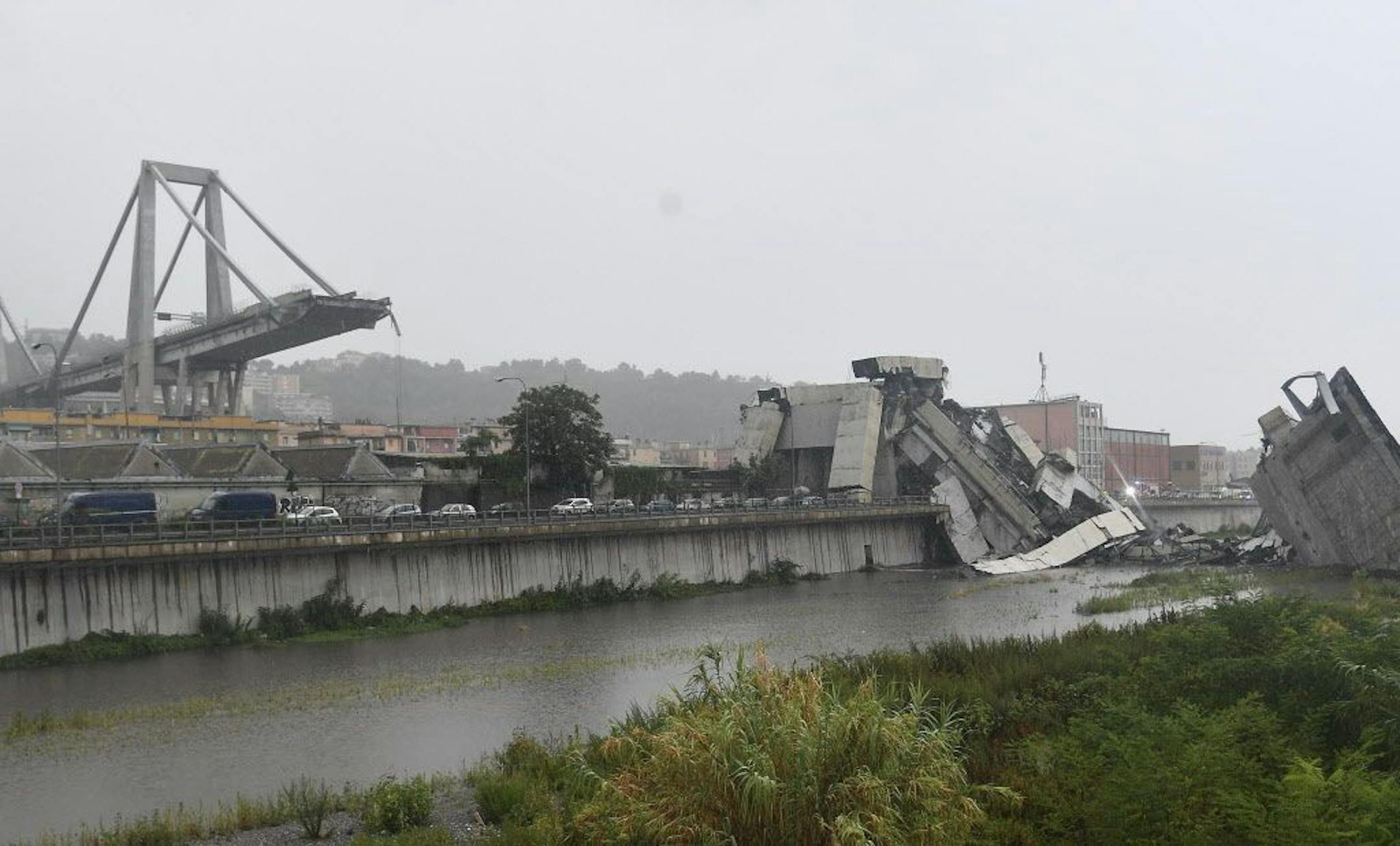 A view of the collapsed Morandi highway bridge in Genoa, northern Italy, Tuesday, Aug. 14, 2018. A large section of the bridge collapsed over an industrial area in the Italian city of Genova during a sudden and violent storm, leaving vehicles crushed in rubble below.
