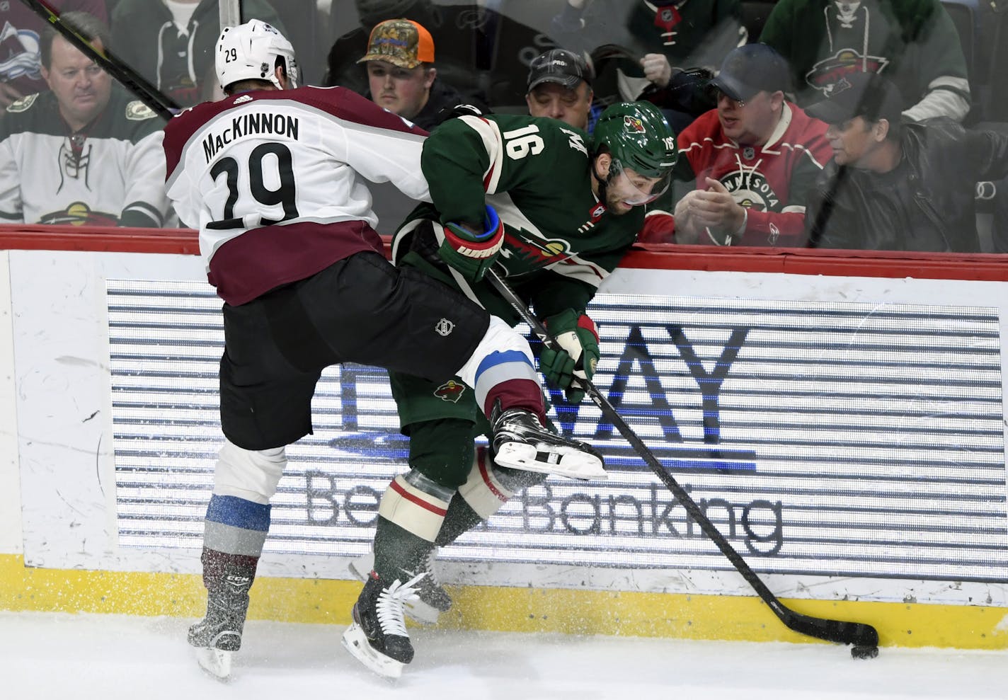 Colorado Avalanche's Nathan MacKinnon (29) pins Minnesota Wild's Jason Zucker (16) to the boards during the third period of an NHL hockey game Sunday, Feb. 9, 2020, in St. Paul, Minn. The Avalanche won 3-2. (AP Photo/Hannah Foslien)