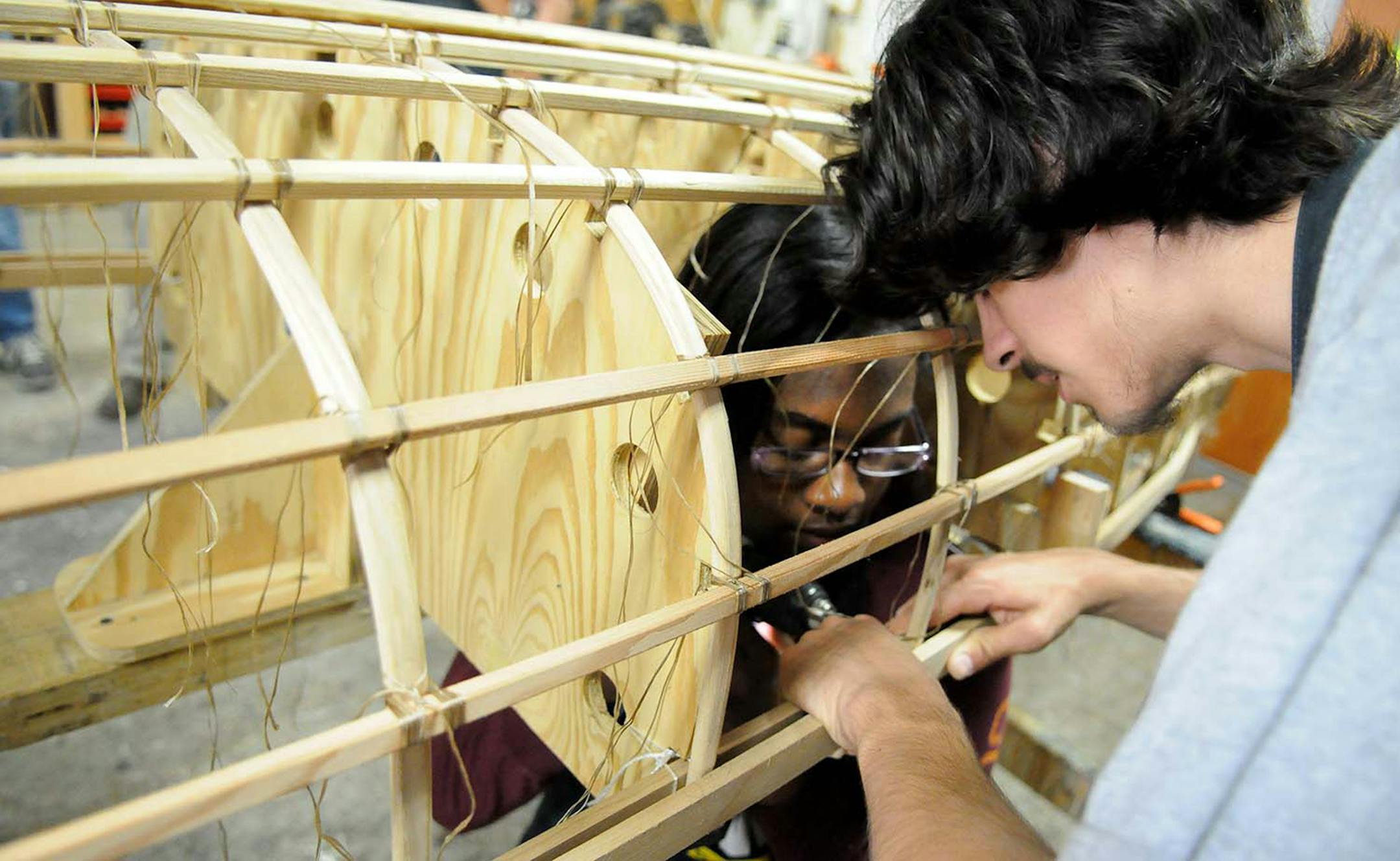 Photo by John Doman
Lanisha Wheatley (L), a junior at River's Edge Academy in St Paul and Andrew Vega, a senior at Jennings Community Learning Center attach ribs to a canoe frame at Urban Boatbuilders in St Paul Thursday afternoon June 19, 2014.