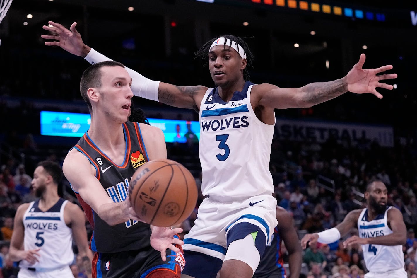 Oklahoma City Thunder forward Aleksej Pokusevski, left, passes in front of Minnesota Timberwolves forward Jaden McDaniels (3) in the second half of an NBA basketball game Friday, Dec. 16, 2022, in Oklahoma City. (AP Photo/Sue Ogrocki)