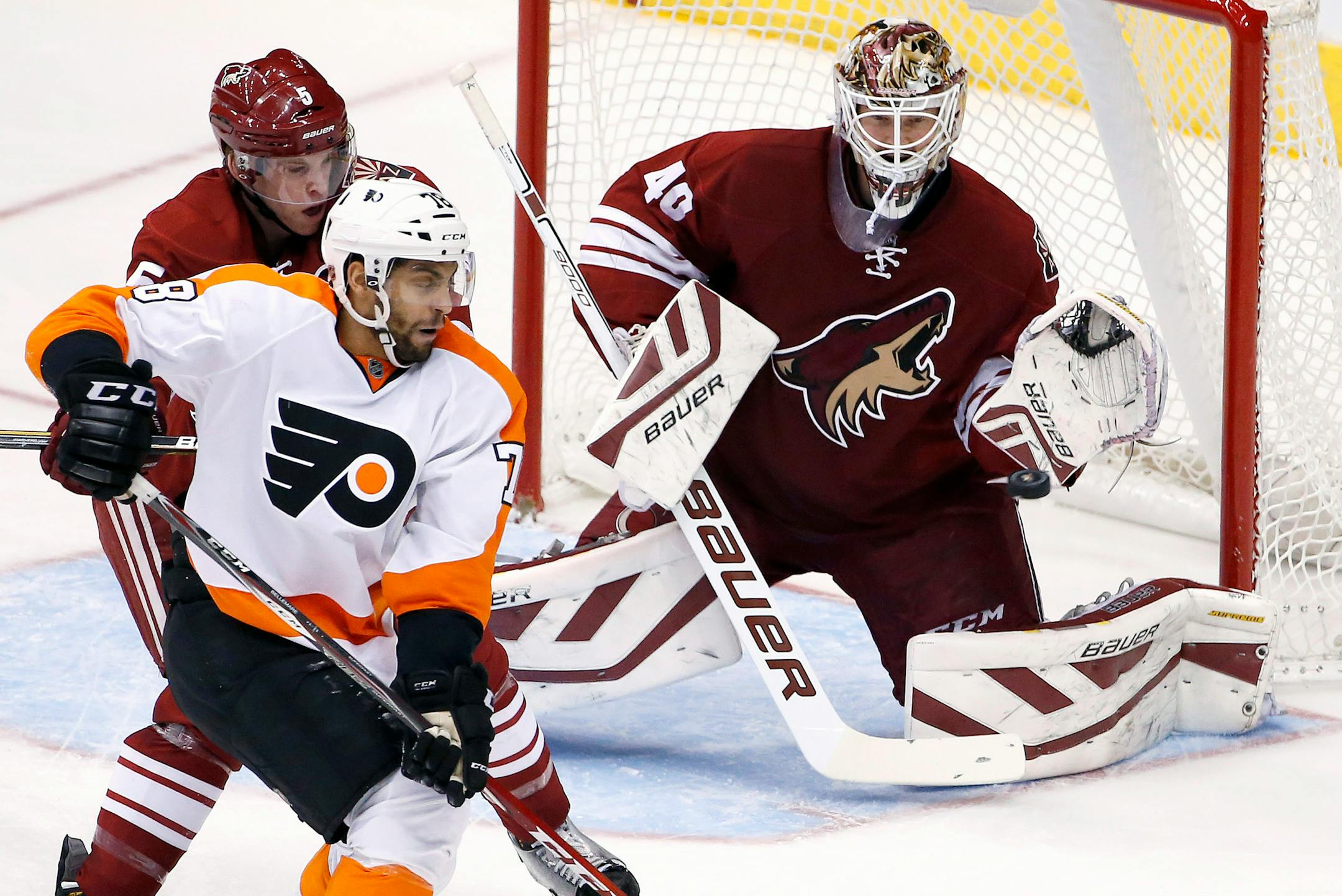 Arizona Coyotes' Devan Dubnyk (40) makes a glove save on a shot as Coyotes' Connor Murphy (5) defends against Philadelphia Flyers' Pierre-Edouard Bellemare (78) during the second period of an NHL hockey game Monday, Dec. 29, 2014, in Glendale, Ariz. (AP Photo/Ross D. Franklin)