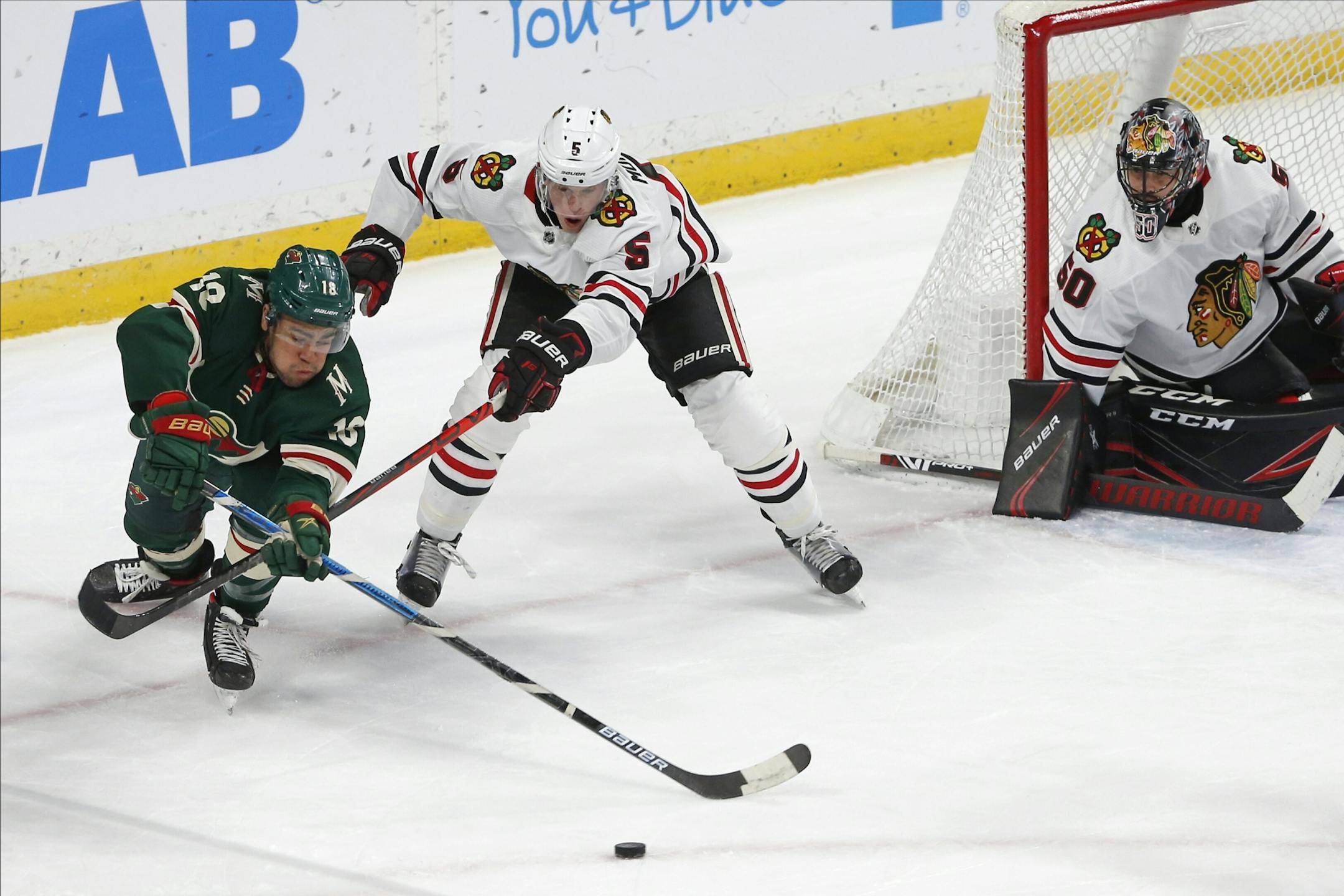 Jordan Greenway, left, chases the puck as Chicago Blackhawks' Connor Murphy defends