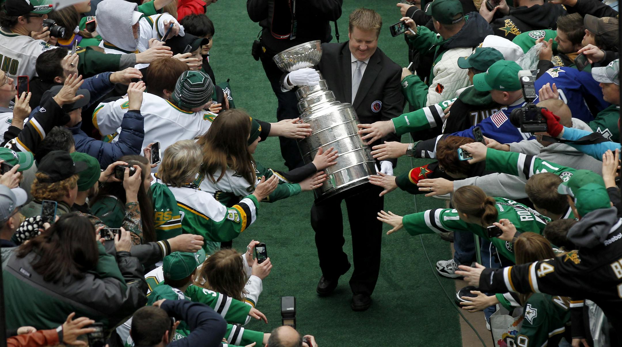 Dallas Stars fans reach for the Stanley Cup before the Mike Modano jersey retirement ceremony before the NHL hockey game between the Stars and the Minnesota Wild on Saturday, March 8, 2014, in Dallas. (AP Photo/The Dallas Morning News, Nathan Hunsinger) MANDATORY CREDIT; MAGS OUT; TV OUT; INTERNET USE BY AP MEMBERS ONLY; NO SALES