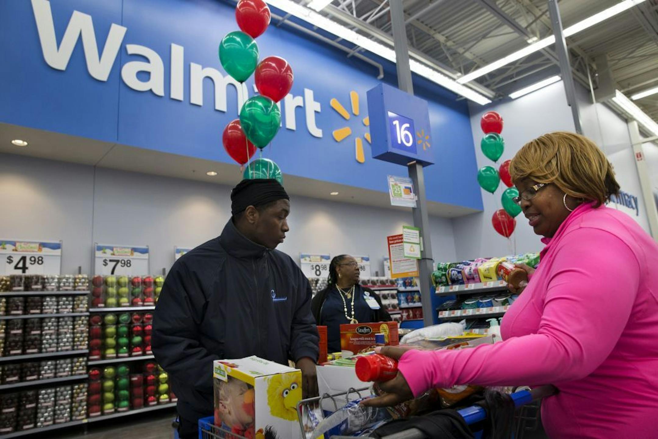 FILE - In this Dec. 4, 2013 file photo, April Taylor of Upper Marlboro, Md., right, buys items with her son Jarhon Taylor, left, on the opening day of a new Wal-Mart in Washington. Wal-Mart Stores Inc. on Thursday, Oct. 30, 2014 said it is considering matching online prices from competitors like Amazon.com, raising the stakes for the holiday shopping season.