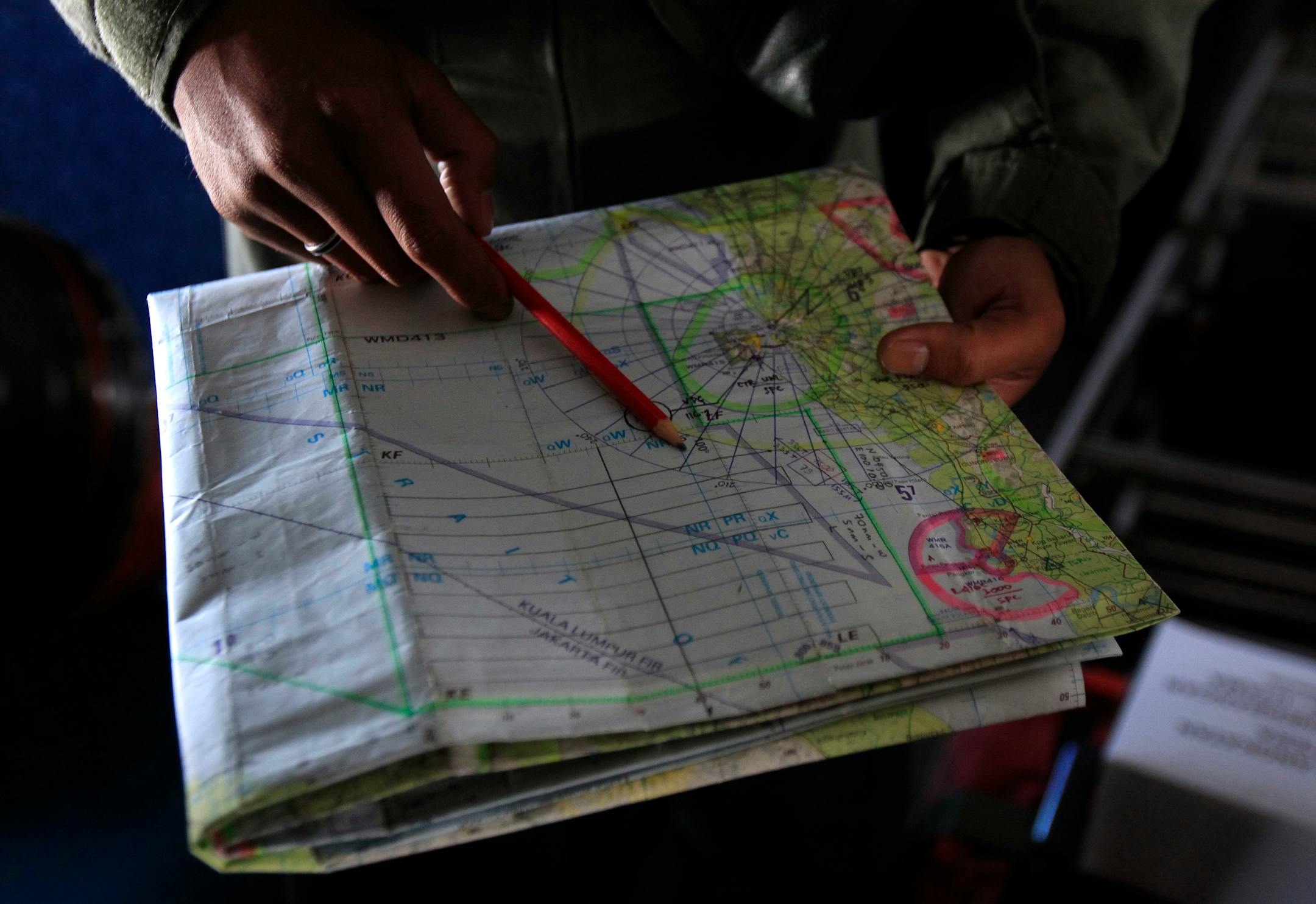 A pilot of a Royal Malaysian Air Force CN-235 aircraft shows a map during a search and rescue operation for the missing Malaysia Airlines plane over the waters at Malacca straits, Malaysia, Thursday, March 13, 2014.