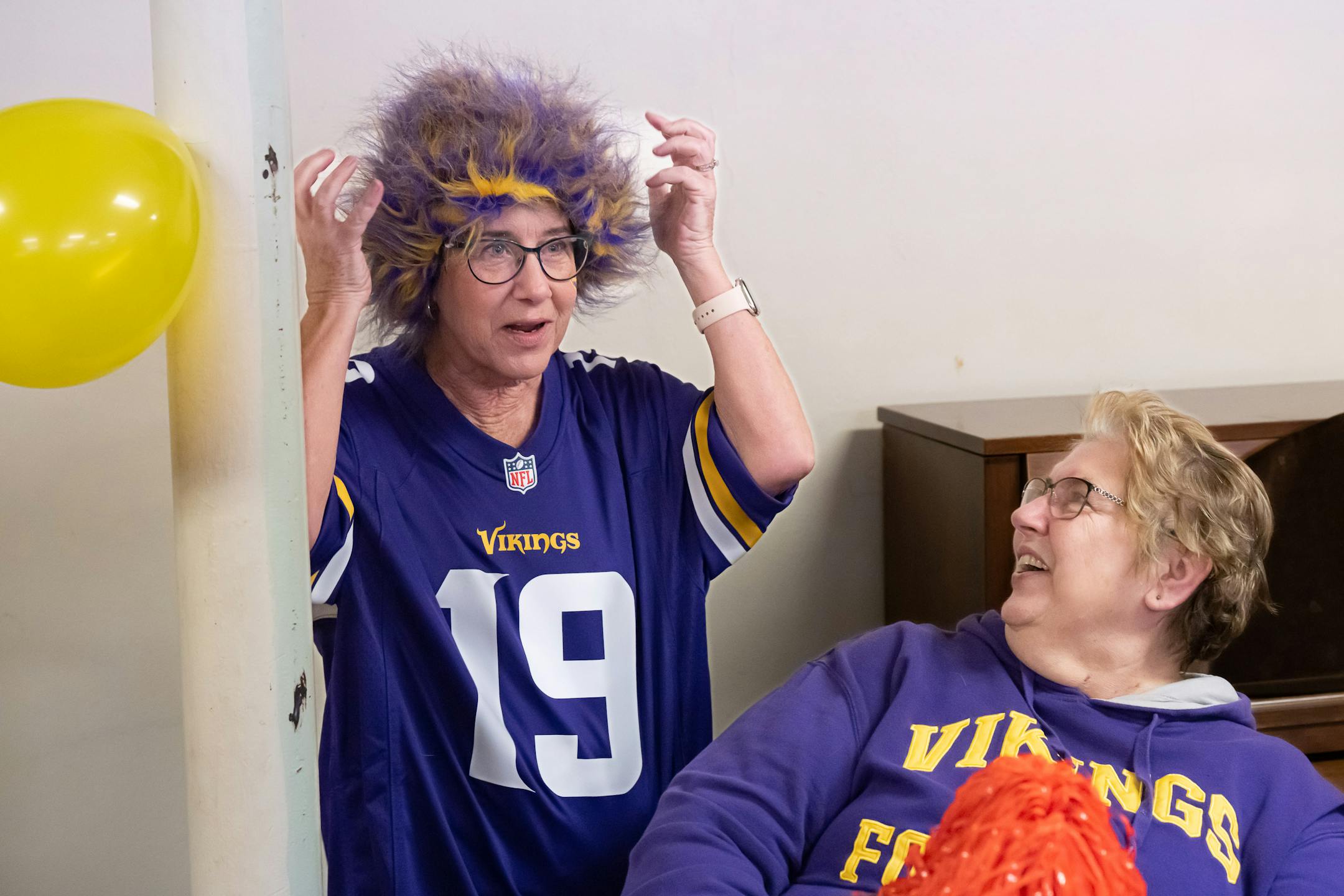Pastor Vicki VanderVegt, left, smiled as she tried on Corrine Meyer's Viking colored wig.