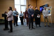 Minneapolis Mayor Jacob Frey, center, flanked by city and police officials, watches at a Wednesday news conference a video advertisement the city rele