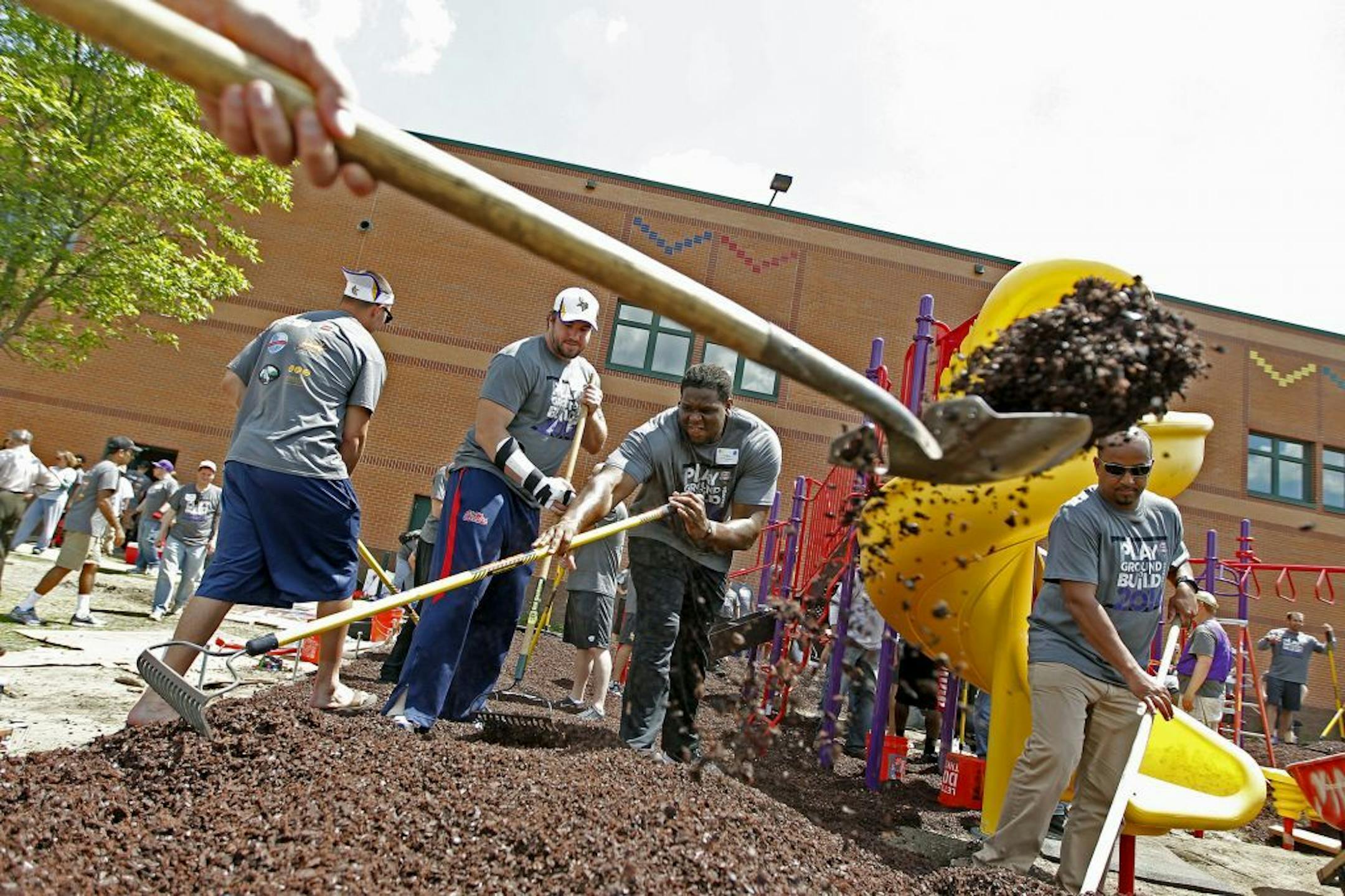 Minnesota Vikings Pierce Burton, left, and Antonio Richardson, center, joined other players, coaches, and school staff to help build a playground at Lucy Craft Laney School during the annual Vikings Playground Build, Wednesday, June 4, 2014 in Minneapolis, MN.