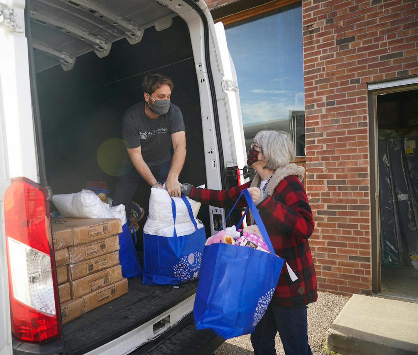 My Very Own Bed founder Michael Allen grabbed bags filled with sheets, blankets, books and toys from Teri Pashina, a teacher with the Tassel Program, who brought a group of volunteers to help.