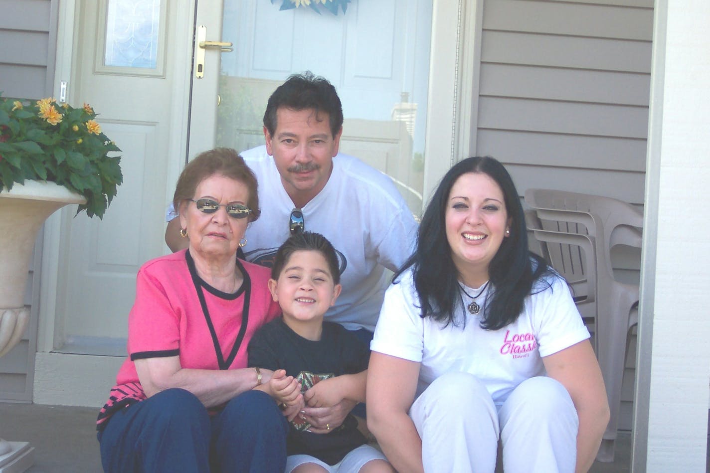 A family sits on the front porch of a suburban home