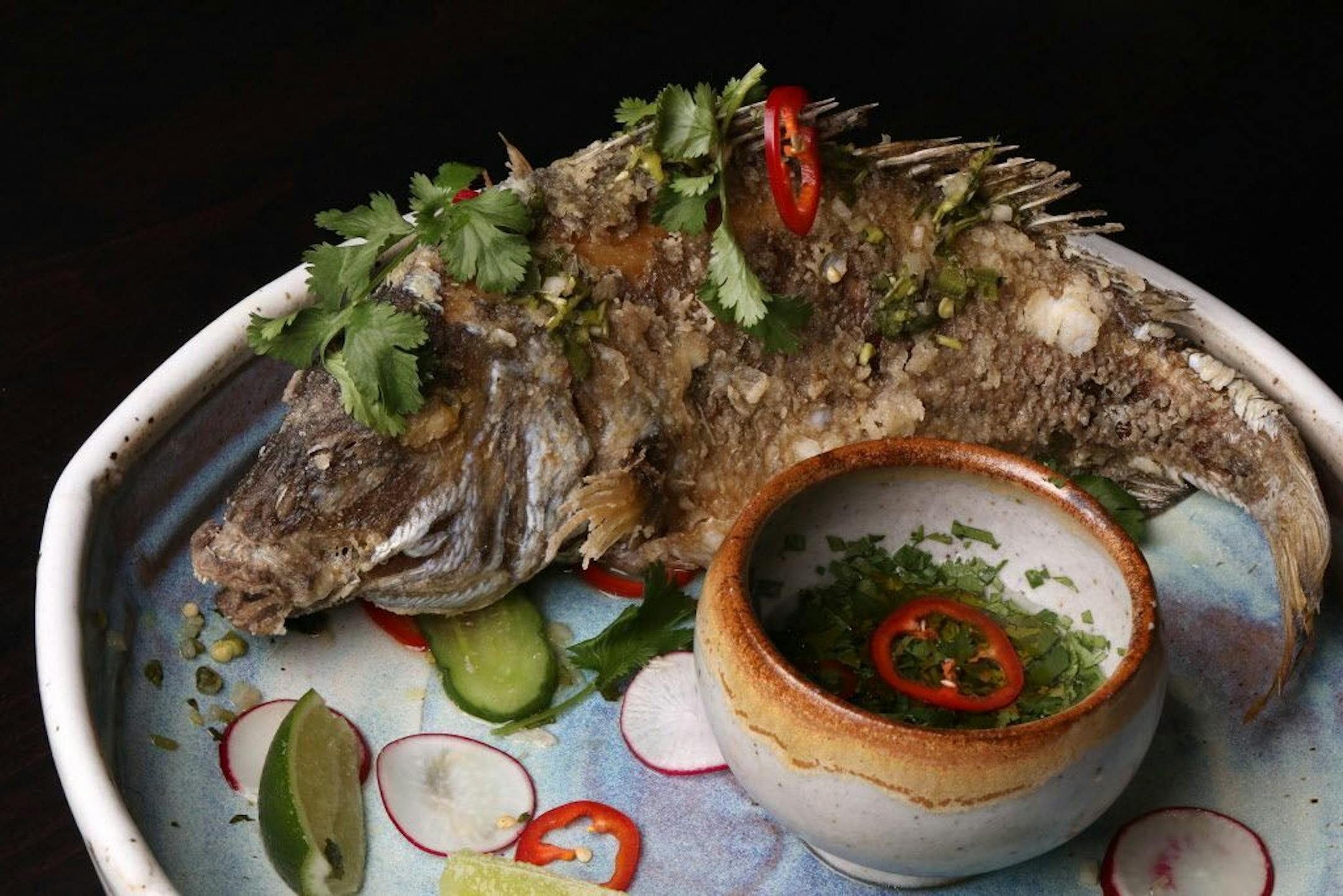 Pictured is the daily whole fish, a Thai fried porgy with nam chim and pickled cucumber.
