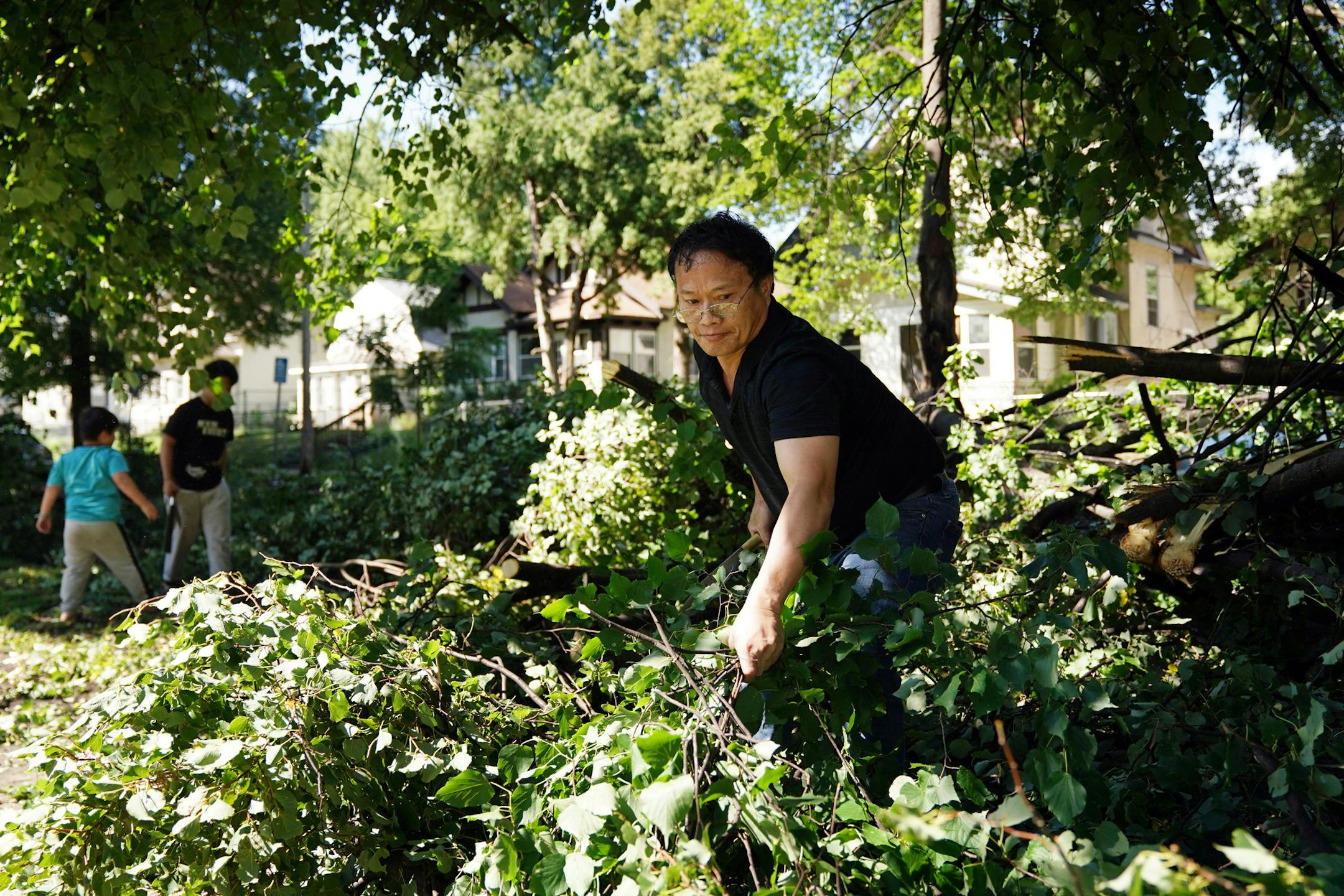 Phai Thao got some help from his two sons, Michael 11, and Keng Kue, 5, as they worked to clear a downed tree from the sidewalk in front of their north Minneapolis home Saturday morning after strong storms overnight toppled several trees in the area. ] ANTHONY SOUFFLE • anthony.souffle@startribune.com Residents and neighbors worked to clear trees from the roadway and sidewalks after winds from an overnight storm topped several Saturday, Aug. 15, 2020 in north Minneapolis.