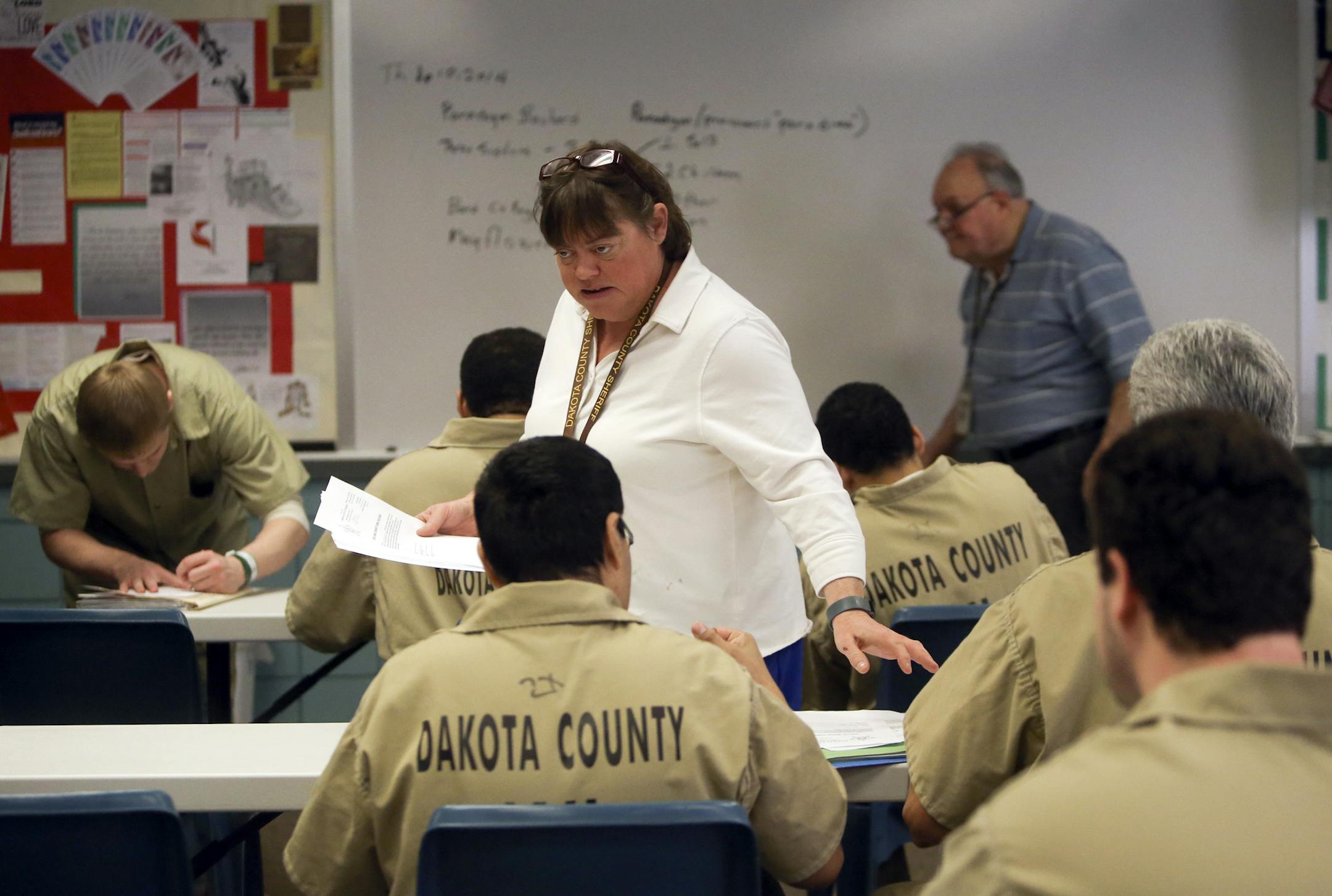 Bill Postiglione, 76, rear right, and Gaby Postiglione, 53, center, taught fractions and decimals to inmates Thursday, April 10, 2014, at the Dakota County Jail in Hastings, MN.The father-daughter team come to the Dakota County jail three times a week (Bill comes in a fourth day, too) to teach GED and college prep classes to inmates. The hardest part, Bill said, is the constant turnover in the jail population. But he loves the work and says he‚Äôll do it until he dies.](DAVID JO