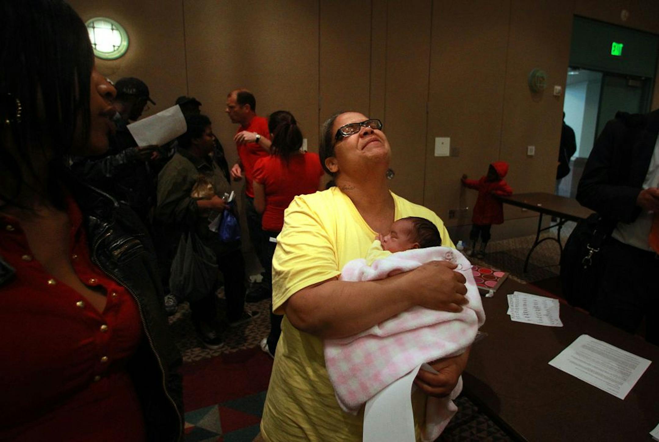 Jayme Day, with 13-day-old Amirianna, paused for a moment as her family sought answers and aid at the Minneapolis Convention Center.