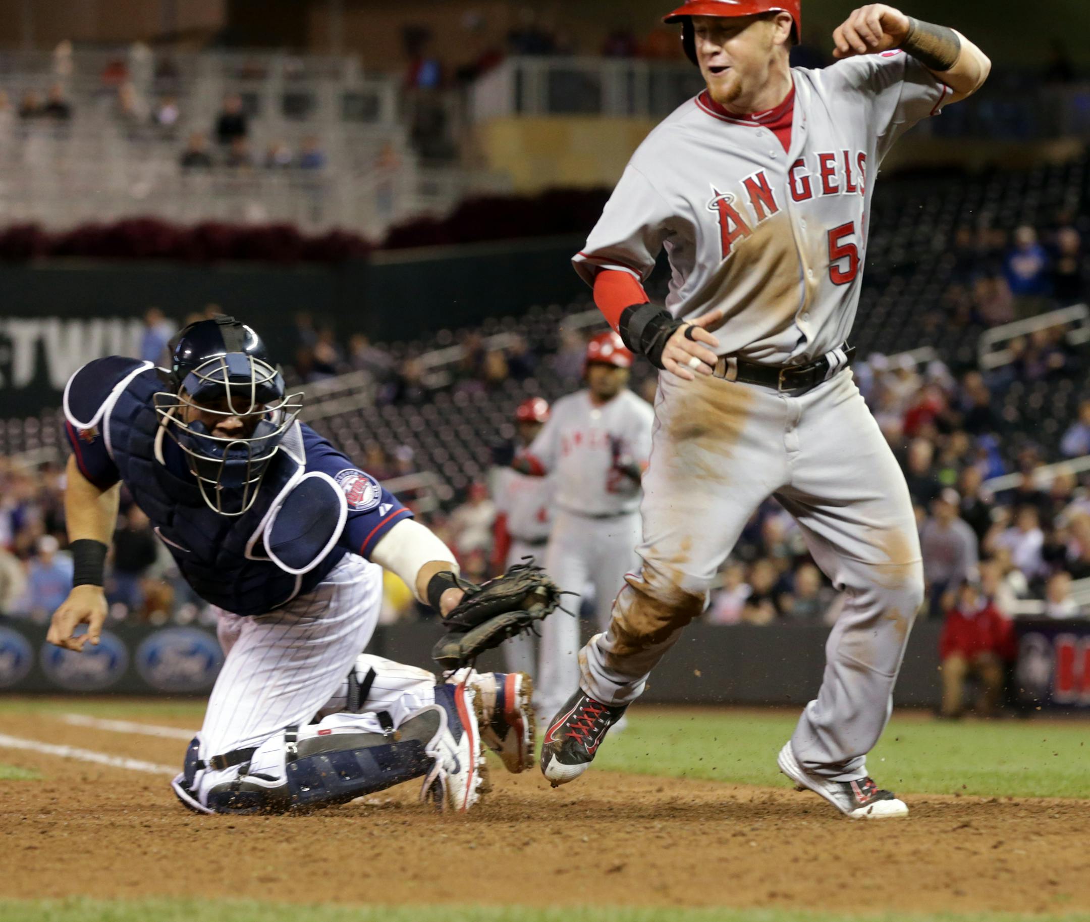 Los Angeles Angels' Kole Calhoun, right, beats the tag by Minnesota Twins catcher Josmil Pintoto score the go-ahead run on a sacrifice fly by Erick Aybar in the 10th inning of a baseball game, Friday, Sept. 5, 2014, in Minneapolis. The Angels won 7-6. (AP Photo/Jim Mone)