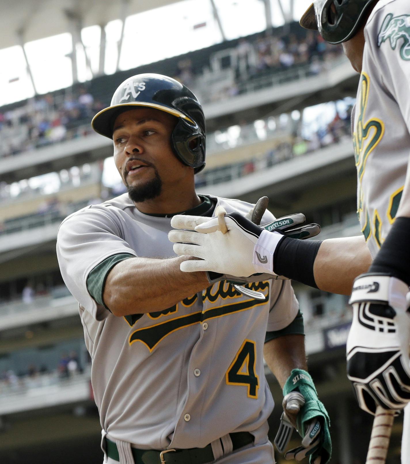 Oakland Athletics' Coco Crisp, left, is congratulated by Yoenis Cespedes after scoring on a single by Jed Lowrie off Minnesota Twins pitcher Scott Diamond in the third inning of a baseball game, Thursday, Sept. 12, 2013 in Minneapolis. (AP Photo/Jim Mone)