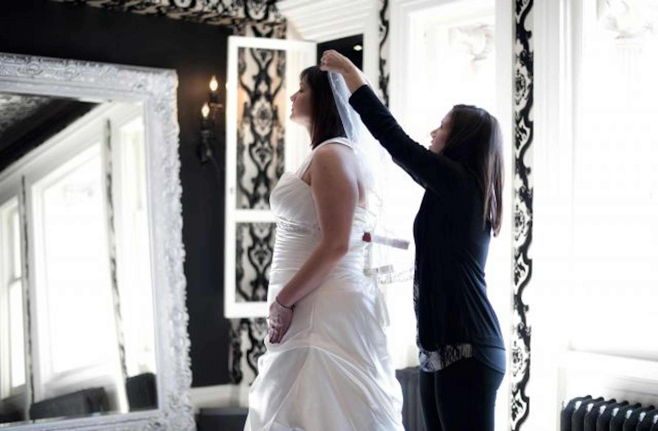 Shayna Clute, owner of Luxe Bridal Couture helped bride Lisa Thompson try on wedding dresses. Luxe caters to plus-sized brides.