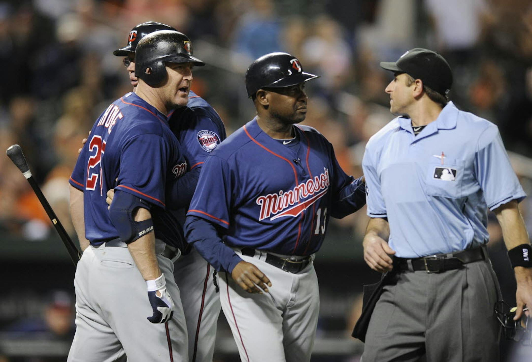 Minnesota designated hitter Jim Thome, left, is restrained by third base coach Steve Liddle as he argues with home plate umpire Chris Guccione, right, after Thome struck out during the eighth inning. First base coach Jerry White is at second from right.