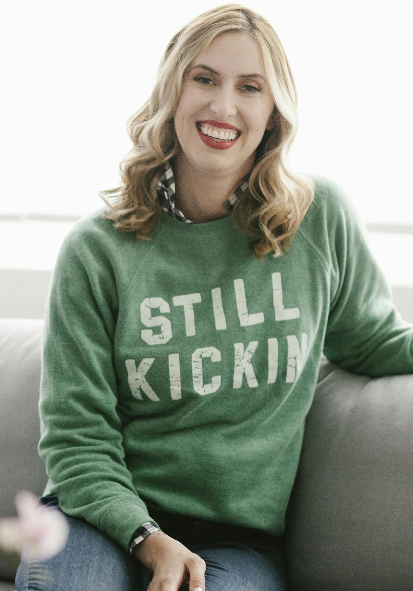 Still Kickin founder Nora McInerny wears one of the sweatshirts her nonprofit sells in order to generate cash grants for people in crisis.