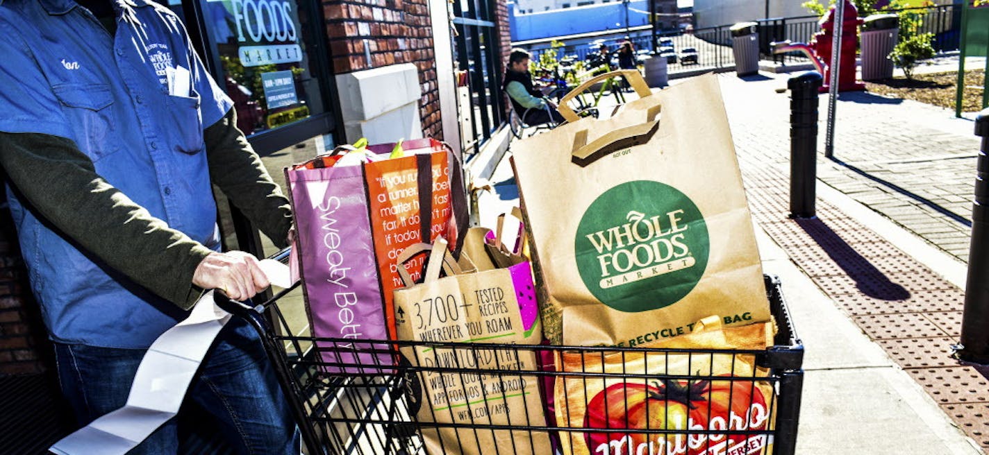 FILE &#xf3; A Whole Foods employee pushes a laden cart out of the store, in New York, Oct. 30, 2015. Amazon&#xed;s $13.4 billion purchase of Whole Foods is a shot across the bow of the grocery-store industry, and shares of Walmart, Target, Kroger and Costco all tumbled in response to the announcement on June 16, 2017. (Dolly Faibyshev/The New York Times)