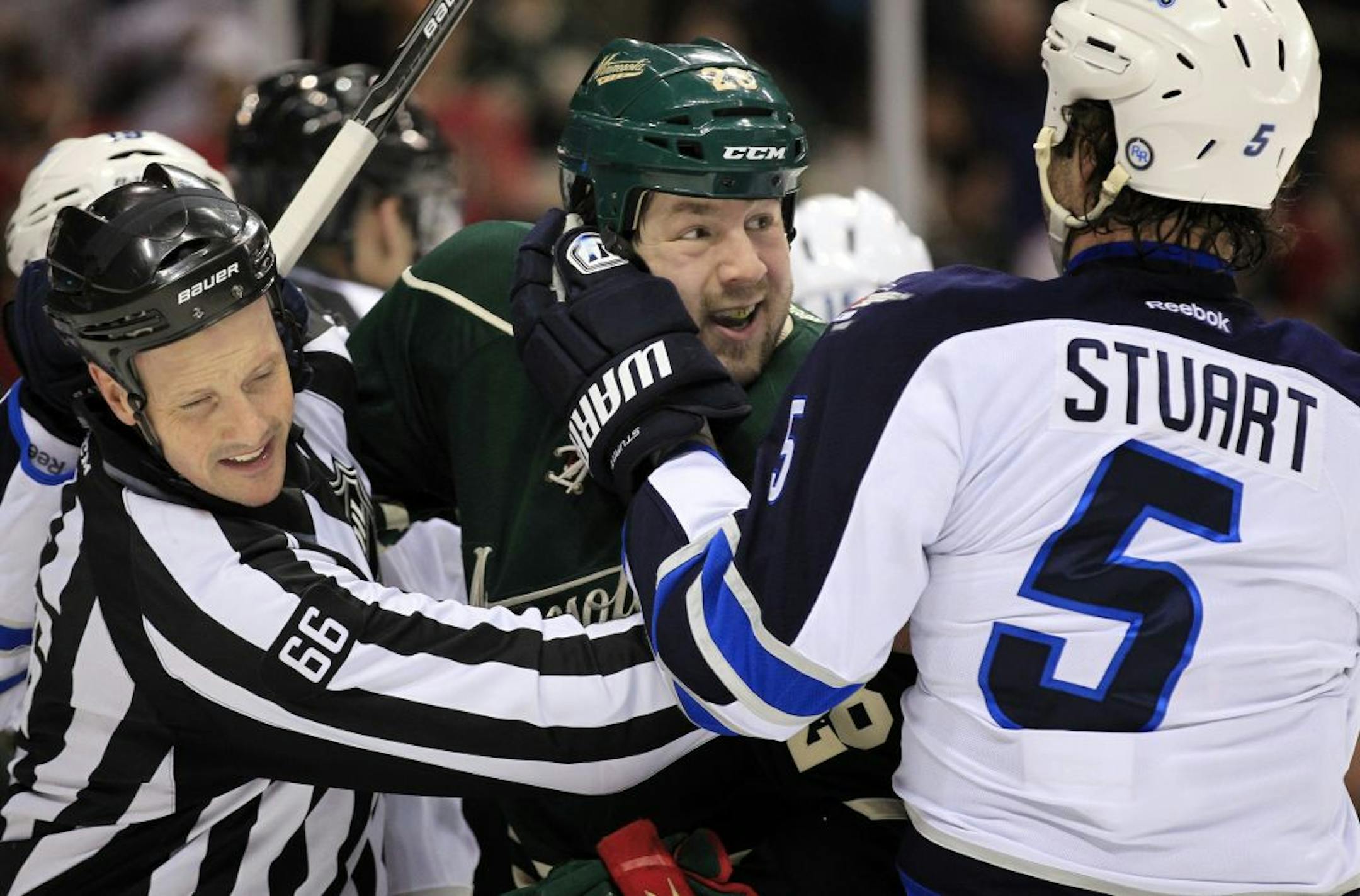 Matt Kassian (28) was held back by linesman Darren Gibbs (66) and Mark Stuart (5) in the first period.