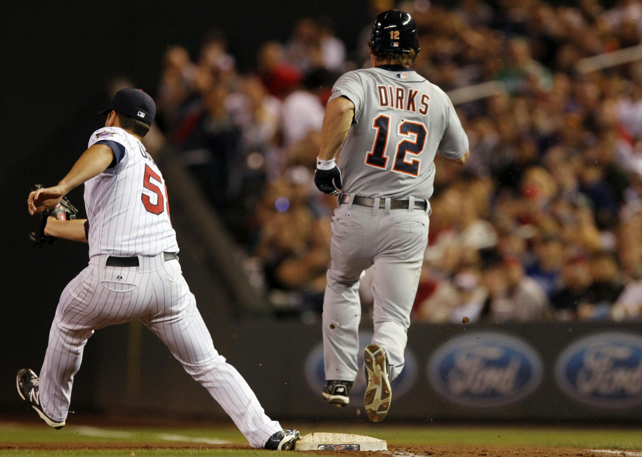 Detroit Tigers' Andy Dirks (12) is safe at first base after hitting a single against Minnesota Twins starting pitcher Scott Diamond, left, who comes up short on the fielder's choice during the fifth inning of a baseball game, Friday, Sept. 28, 2012, in Minneapolis.
