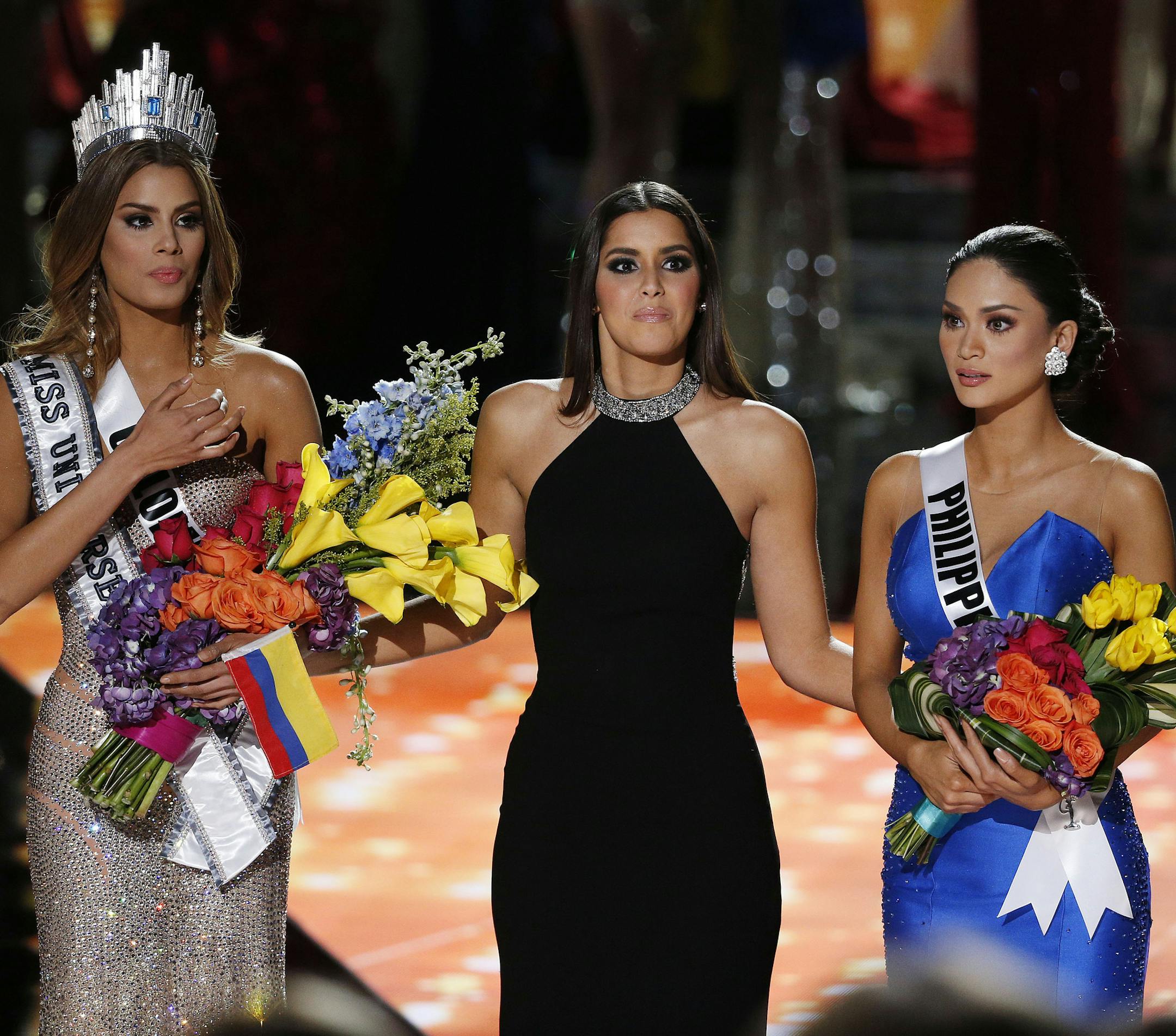 Former Miss Universe Paulina Vega, center, reacts before taking away the flowers, crown and sash from Miss Colombia Ariadna Gutierrez, left, before giving it to Miss Philippines Pia Alonzo Wurtzbach at the Miss Universe pageant Sunday, Dec. 20, 2015, in Las Vegas.