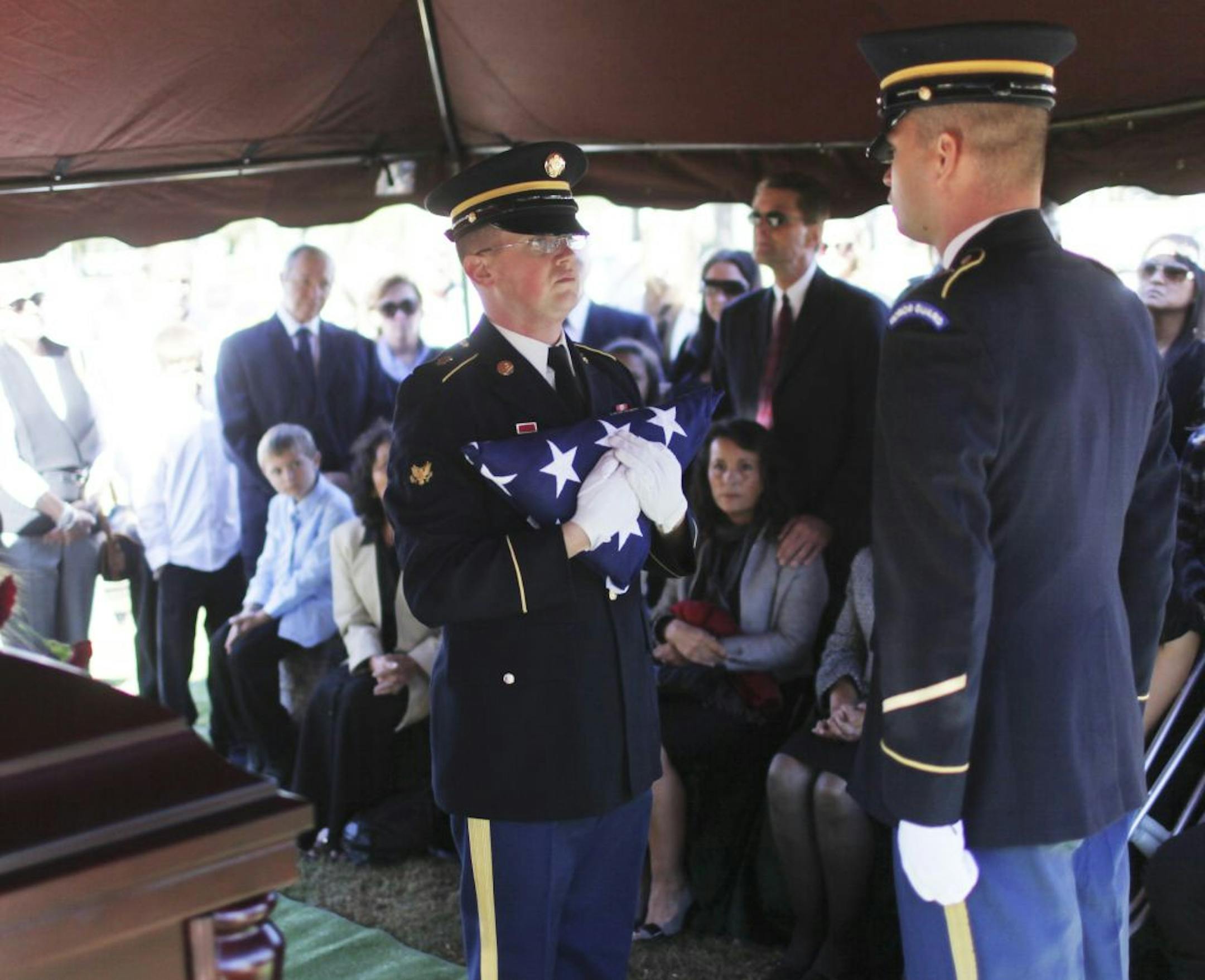 Two of Minnesota's Military Funeral Honor Guard members who served at the funeral of World War II Army vet Edwin G. Laumann during his interment at Holy Trinity Catholic Church Cemetery in Winsted, MN, prepared to present the flag to family members. "It's always about the family and not what we do," one said. Both men, who serve as full time honor guards for military funerals will most likely, they say, be out of a full-time job in October when cuts are expected to take effect. The funeral was p