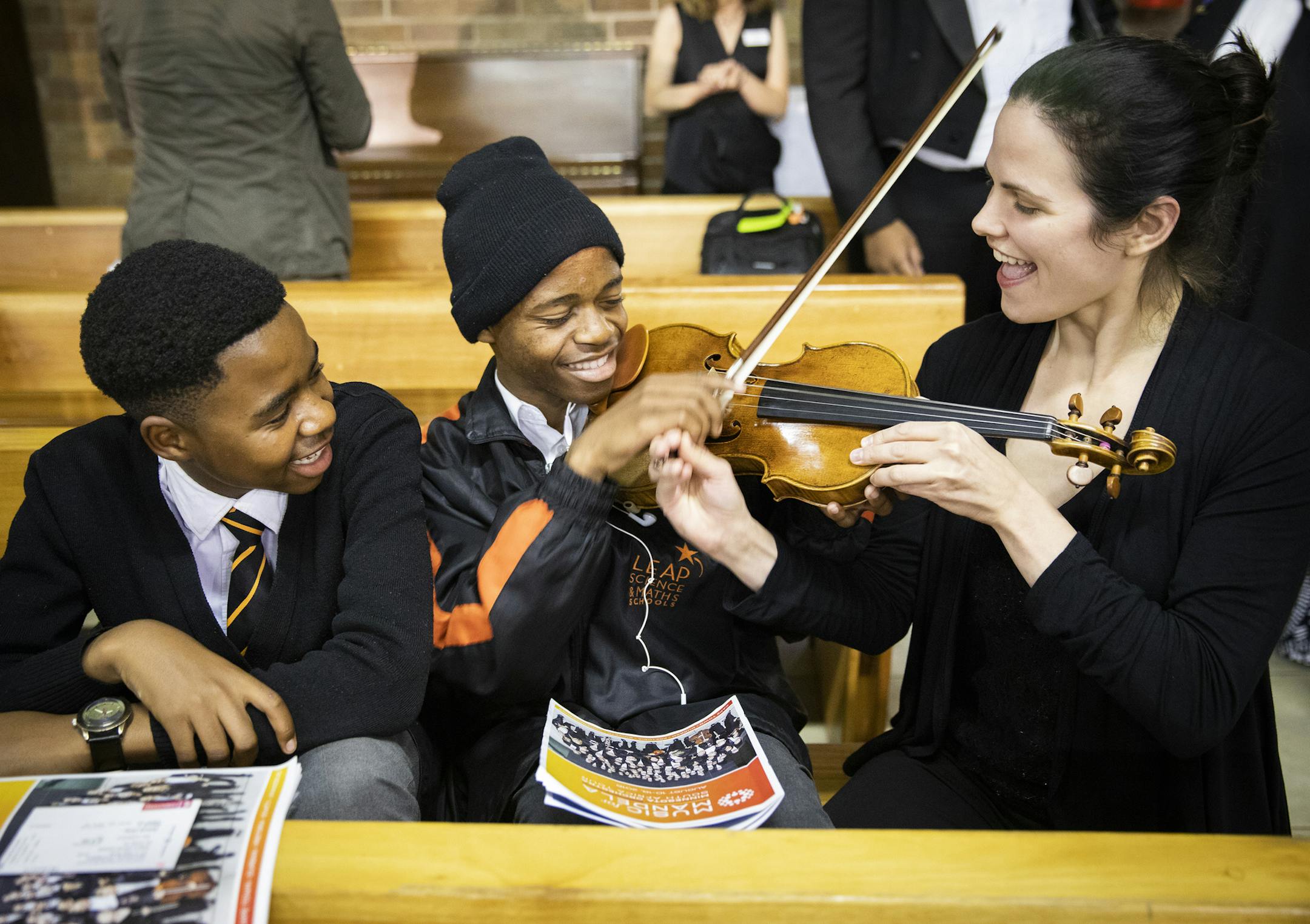 Minnesota Orchestra violin player Alexandra Early shows Emanual Raseokaja, 16, center, how to play her violin as his schoolmate Bosele Seanego, 15, looks on. ] LEILA NAVIDI ï leila.navidi@startribune.com BACKGROUND INFORMATION: The Minnesota Orchestra performs a concert at Regina Mundi Church in Soweto, South Africa on Friday, August 17, 2018.
