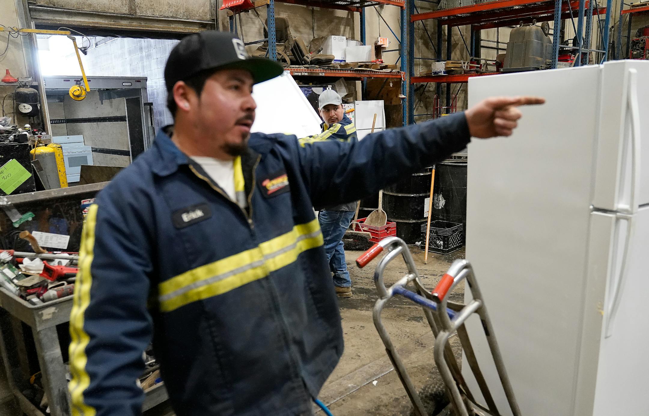 J.R.'s Advanced Recyclers dock supervisor Erick Perez, front, directs a fellow worker where to move an old refrigerator for recycling.