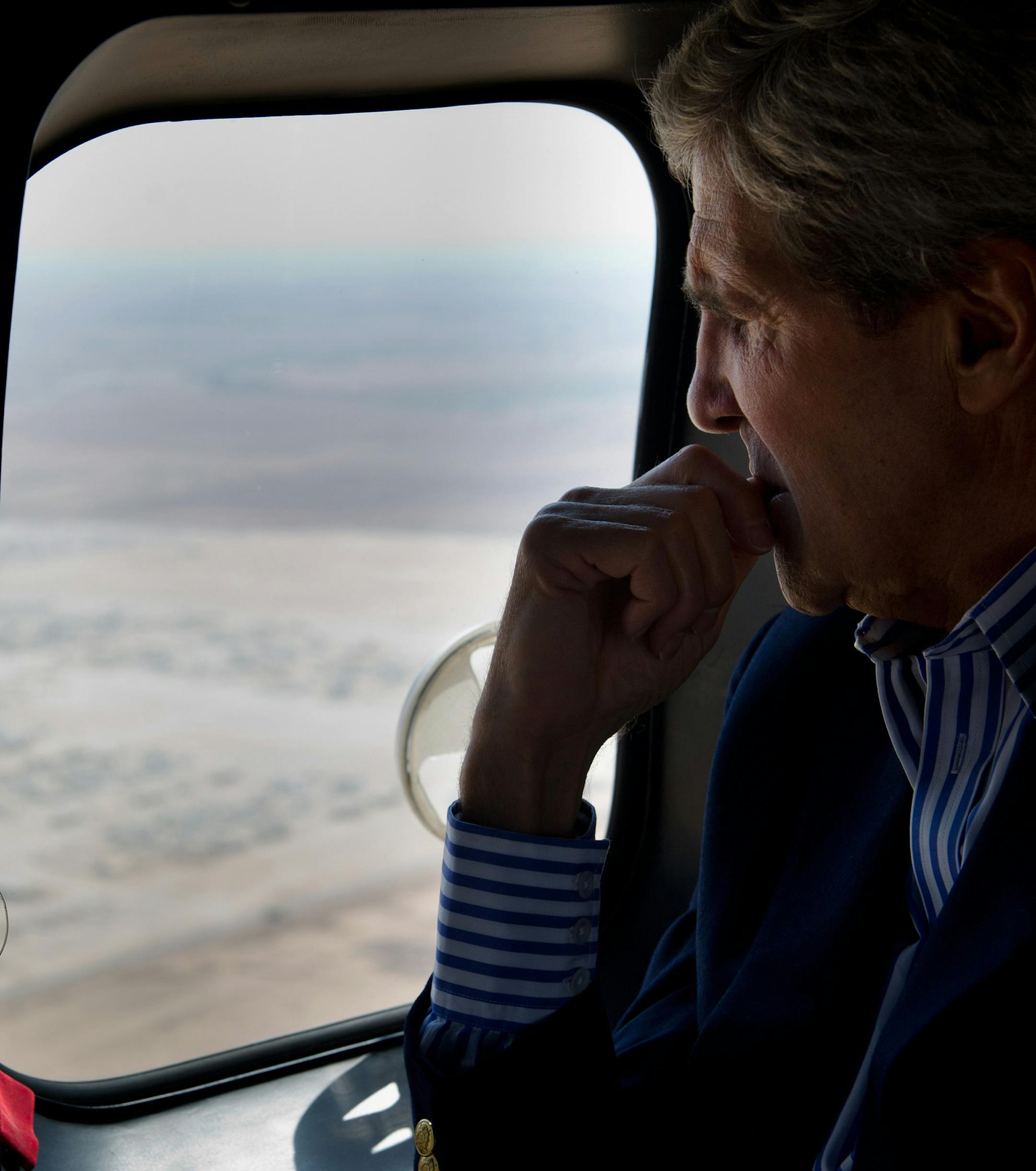 U.S. Secretary of State John Kerry looks out of a helicopter's window as flying to Zaatari refugee camp in Mafraq, Jordan, Thursday, July 18, 2013. Angry Syrian refugees urged Kerry on Thursday to do more to help and protect opponents of President Bashar Assad's government, venting frustration at perceived inaction on their behalf. (AP Photo/Mandel Ngan, Pool)