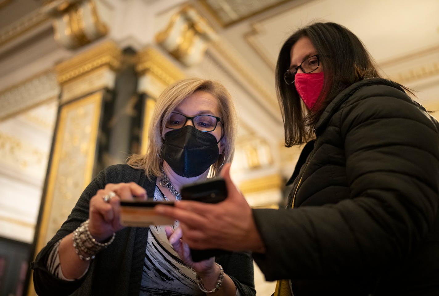 Gail Nelson with the Hennepin Theatre Trust, left, checked the ID of Dorothy Hamman after seeing her vaccination status in an app on her phone in the lobby of the State Theatre Wednesday, Jan. 12, 2022 in Minneapolis, Minn. Theatergoers who want to streamline their entry to the show "Come From Away" at the Orpheum Theatre can show their proof of vaccination just down the street at the State Theatre and obtain a wrist band. Minneapolis and St. Paul both announced a proof of vaccination or negative test requirement for anyone entering a bar, restaurant, or venue, starting January 19. The Hennepin Theatre Trust already had such a policy in effect. ] JEFF WHEELER • Jeff.Wheeler@startribune.com