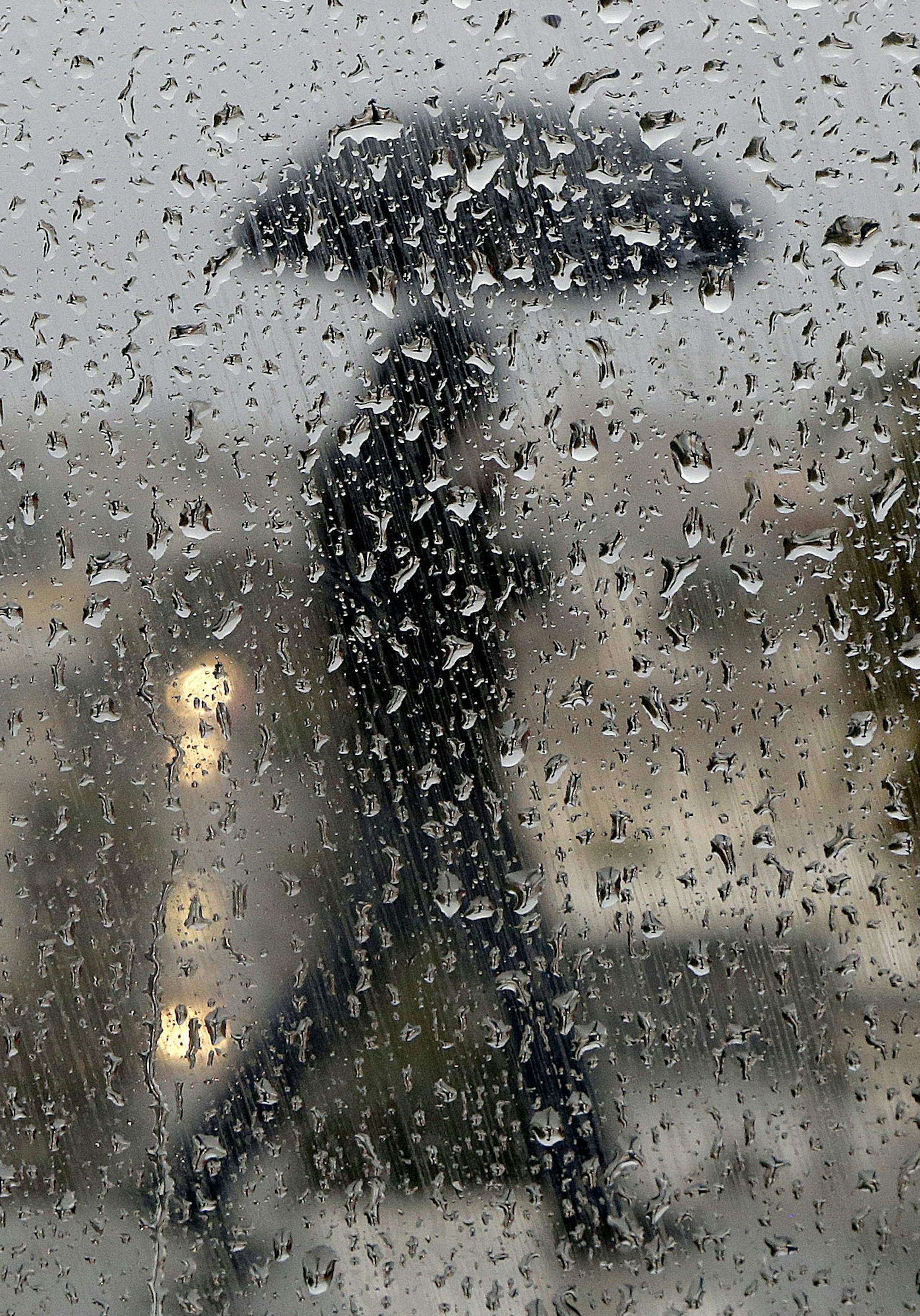 Raindrops appear on a window as a man crosses a street in San Francisco, Wednesday, Jan. 4, 2017. Wet winter weather slammed much of the West on Wednesday, with storms dropping several inches of snow on one Oregon city and several feet of the white stuff predicted high in the Sierra Nevada. (AP Photo/Jeff Chiu) ORG XMIT: CAJC104