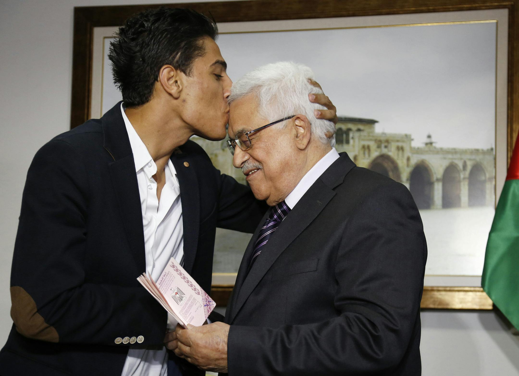 Arab Idol Mohammed Assaf, left, kisses Palestinian President Mahmoud Abbas as he hands him a diplomatic Palestinian Authority passport during their meeting in the West Bank city of Ramallah, Monday, July 1, 2013. Assaf, the 23-year-old from the Gaza Strip who won the popular pan-Arab song contest last month, met Abbas on Monday before performing in Ramallah. (AP Photo/Mohamad Torokman, Pool)